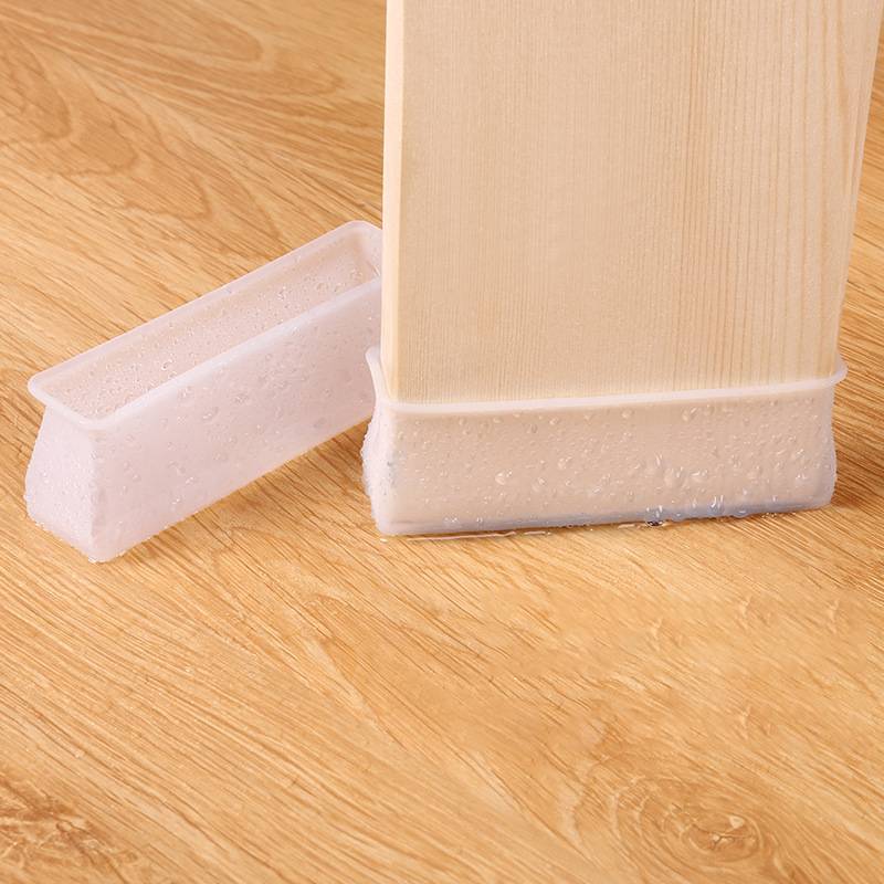 Nahaufnahme eines Möbelbeins in einer schützenden Silikon-Bodenschutzmatte auf einem Holzboden, mit einer Ersatzkappe daneben.