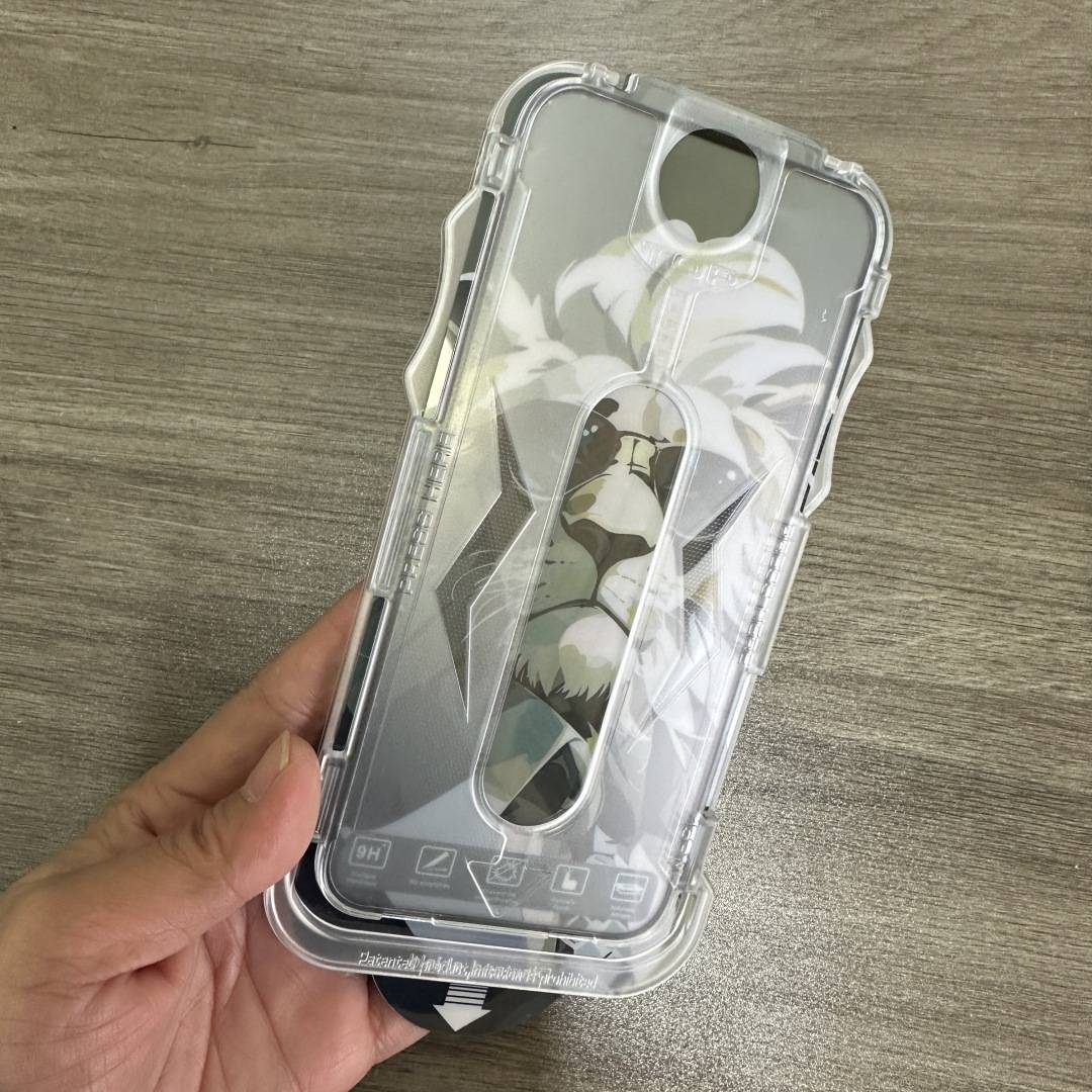 Hand, die eine transparente Schutzhülle für das Telefon mit einem Blumen- und Tiermuster-Einsatz auf einer Holzoberfläche hält.