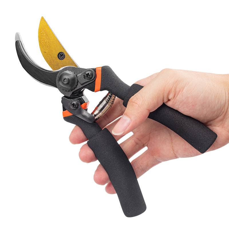 Hand mit schwarzen und orangefarbenen Gartenscheren mit gekrümmten Klingen auf weißem Hintergrund.