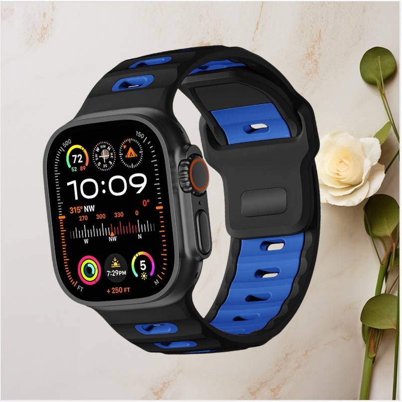 Schwarze und blaue Smartwatch mit digitalem Display, das 10:09 anzeigt, neben Fitness- und Kompass-ähnliche Widgets, daneben eine weiße Blume und grüne Blätter.