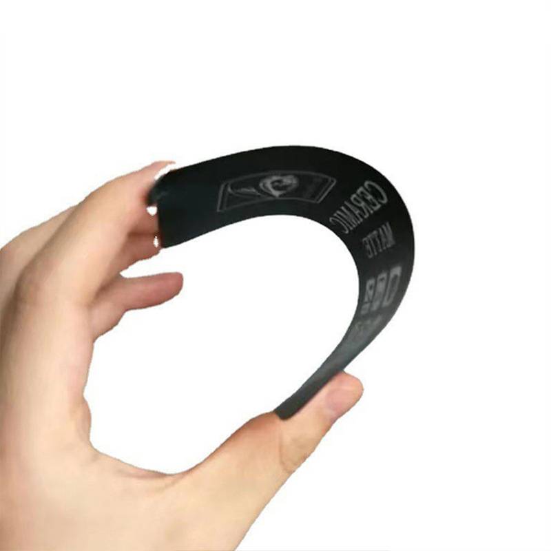 Eine Hand, die einen flexiblen schwarzen Streifen oder ein schwarzes Band mit gedruckten Markierungen gegen einen einfachen weißen Hintergrund biegt.