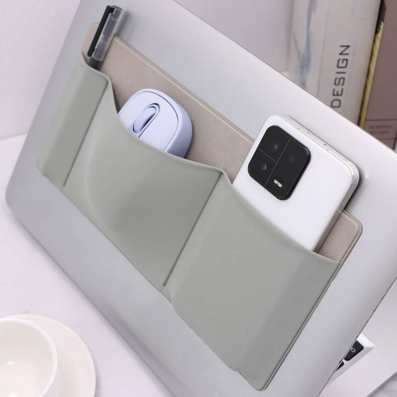 Ein minimalistischer Schreibtischorganizer mit einer vorderen Tasche, die ein weißes Smartphone und eine kabellose Maus hält, vor einem hellen Arbeitsplatz-Hintergrund.