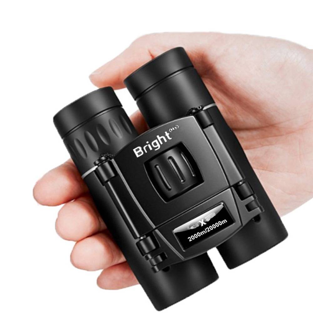 Hand hält ein kompaktes schwarzes Bright-Fernglas-Set mit der Bezeichnung 200m/2000m.