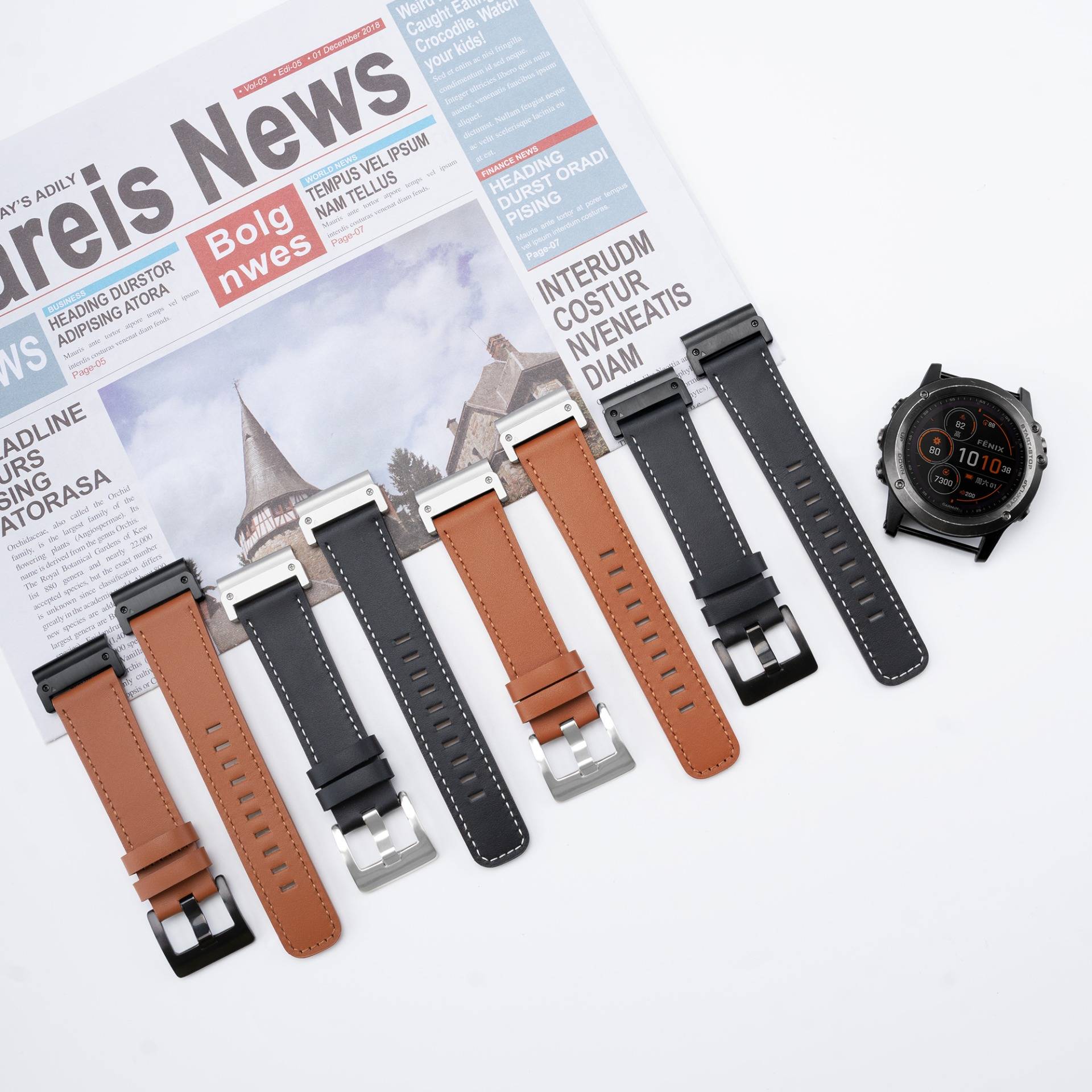 Sortierte Ersatz-Uhrenarmbänder in schwarzem und braunem Leder und Silikon, plus ein schwarzes Smartwatch-Zifferblatt, arrangiert auf einem Zeitungshintergrund.
