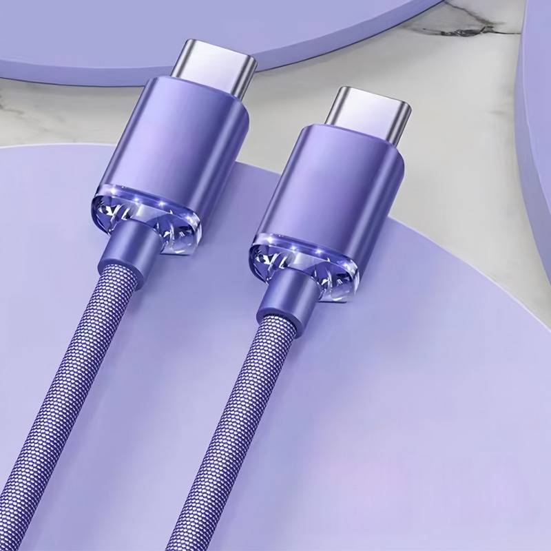 Zwei violette geflochtene USB-C-Ladekabel mit metallischen Steckern auf einer lavendelfarbenen Oberfläche.