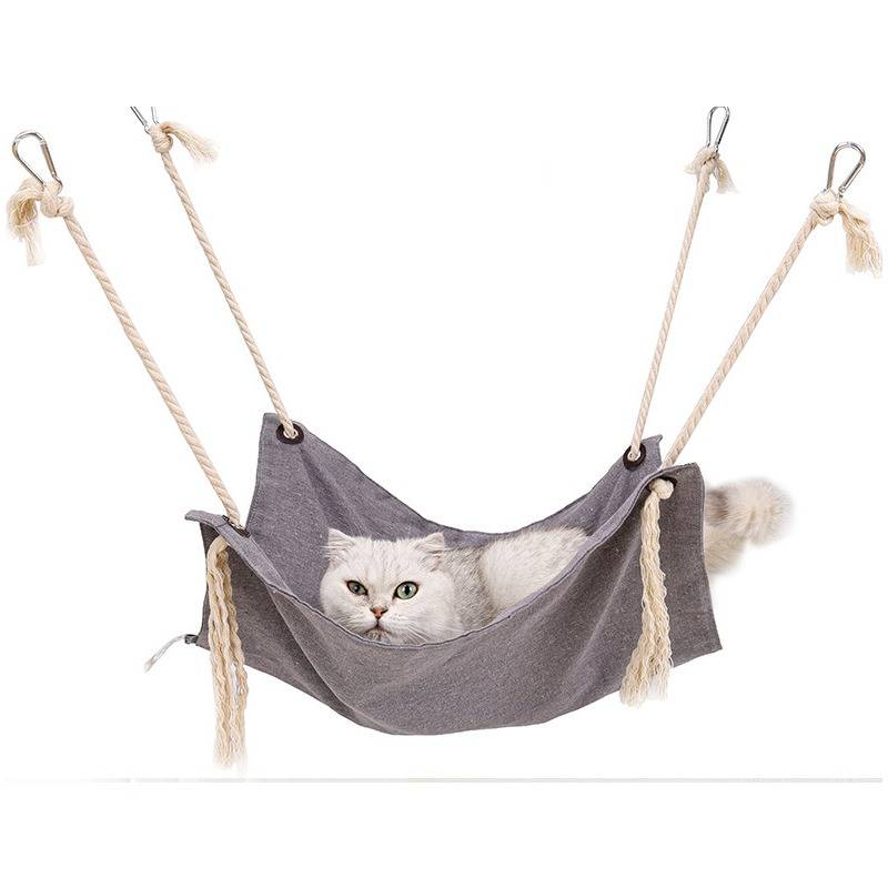 Weiße Katze ruht in einer hängenden grauen Seilhängematte für Haustiere vor weißem Hintergrund.