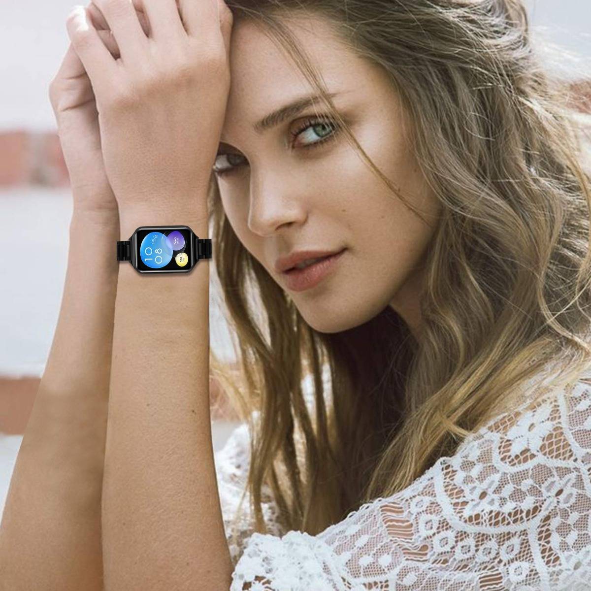 Frau, die mit einer Smartwatch am Handgelenk posiert und einen bunten, kreisförmigen App-Bildschirm zeigt.