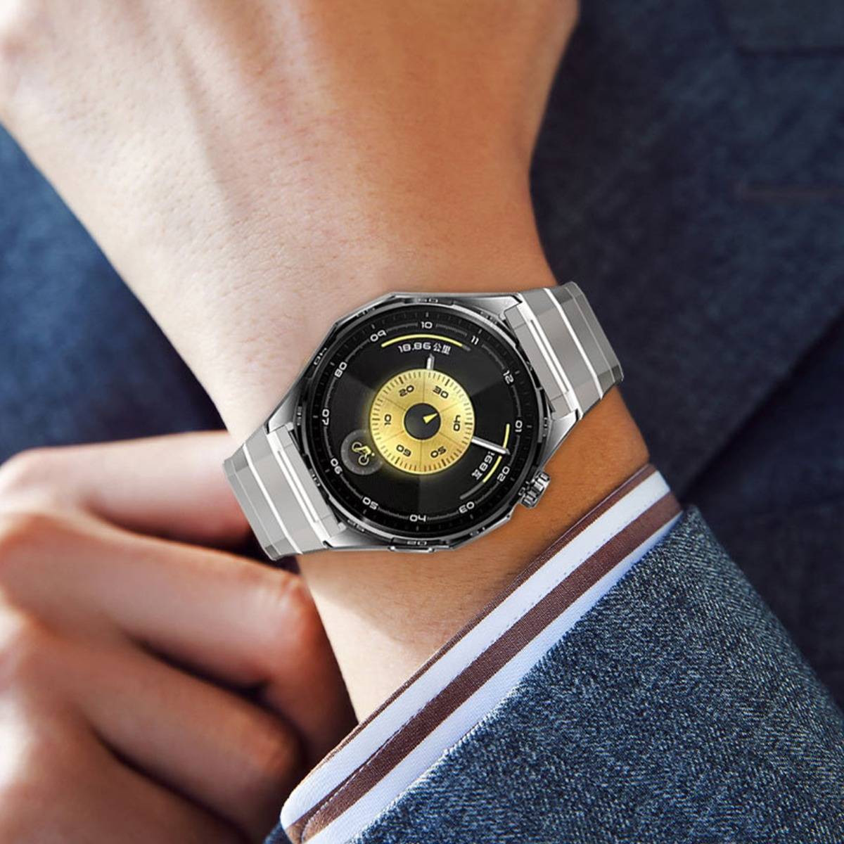 Nahaufnahme einer Person, die eine silberne analoge Armbanduhr mit schwarzem und goldenem Zifferblatt trägt, gezeigt gegen eine Anzugmanschette.