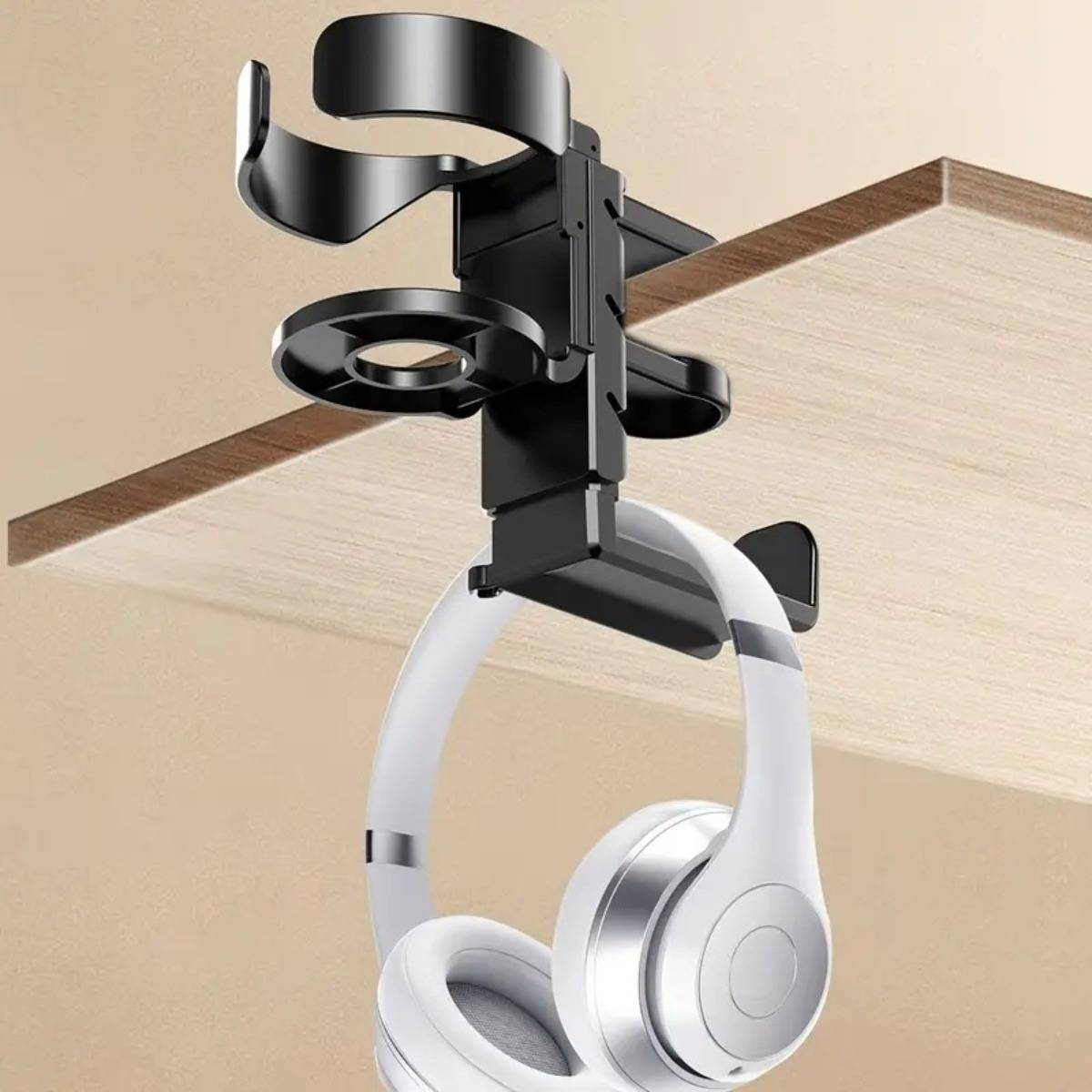 Weiße Over-Ear-Kopfhörer, die an einem schwarzen Clip-Halter unter dem Schreibtisch hängen, der an einer Regalkante montiert ist und ein Kopfhörer-Aufbewahrungszubehör zeigen.
