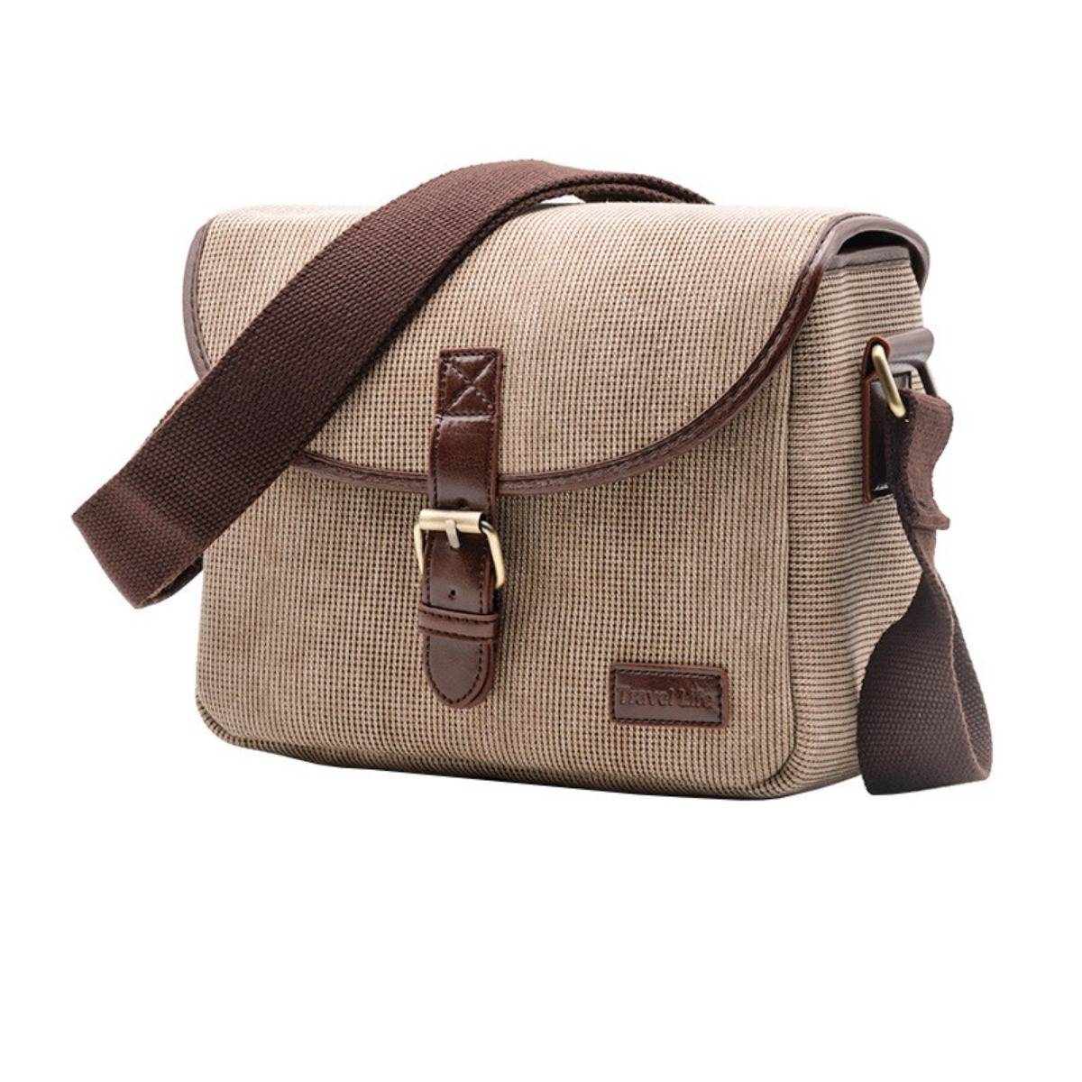 Beige-farbene Leinwandschultertasche mit braunem Ledereinfassung und Klapperikelverschluss auf weißem Hintergrund.