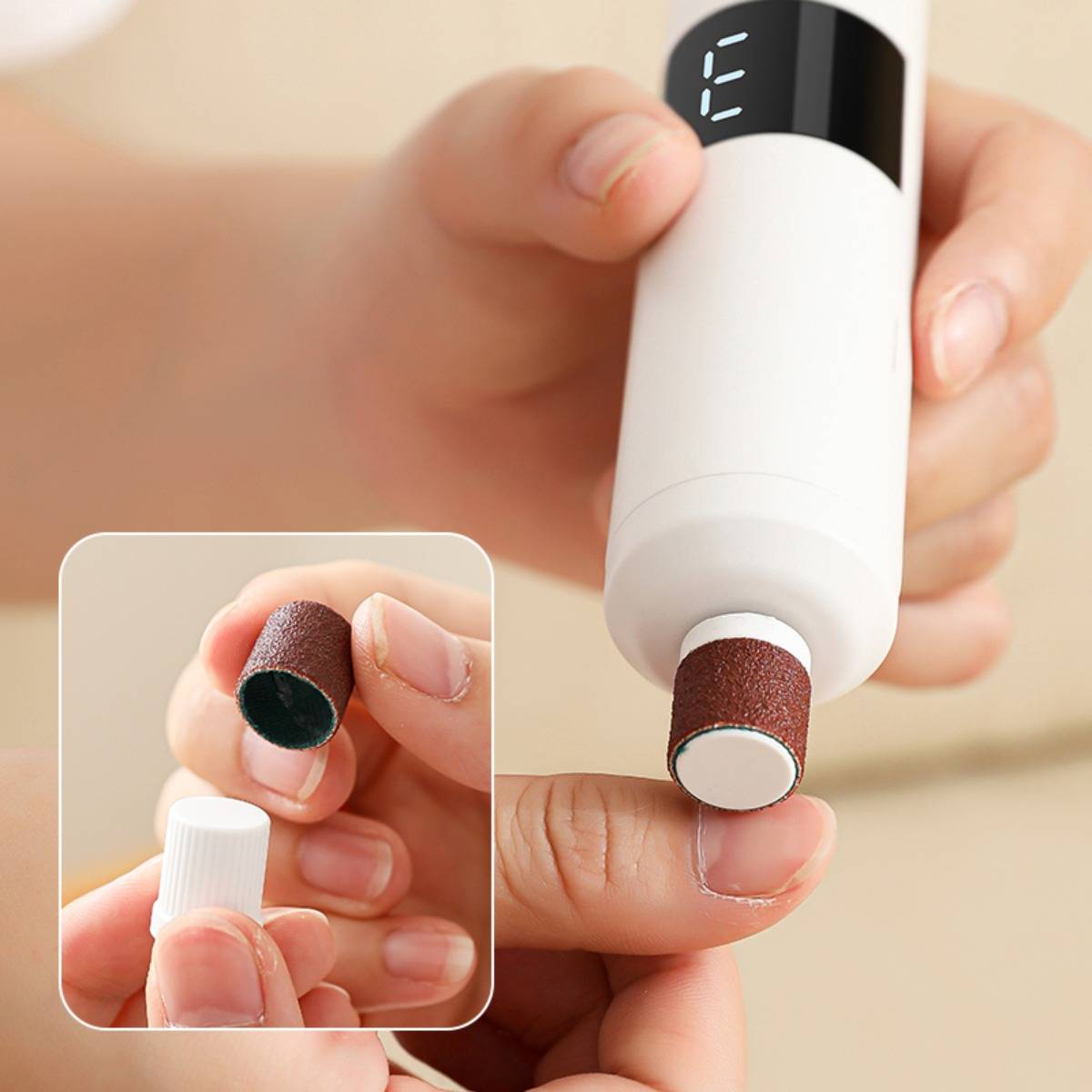 Nahaufnahme einer tragbaren elektrischen Nagelfeile, die Gellack von einem Fingernagel entfernt, mit einer Vergrößerung, die zeigt, wie der Schleifaufsatz auf dem Gerät angebracht wird.