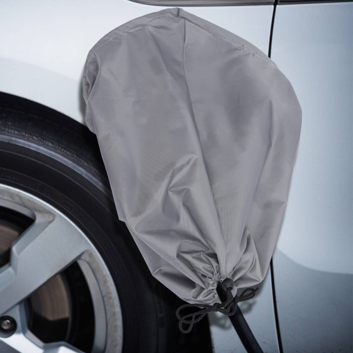 Graue Schutzabdeckung über einem Autoreifen während er gewartet oder gereinigt wird.