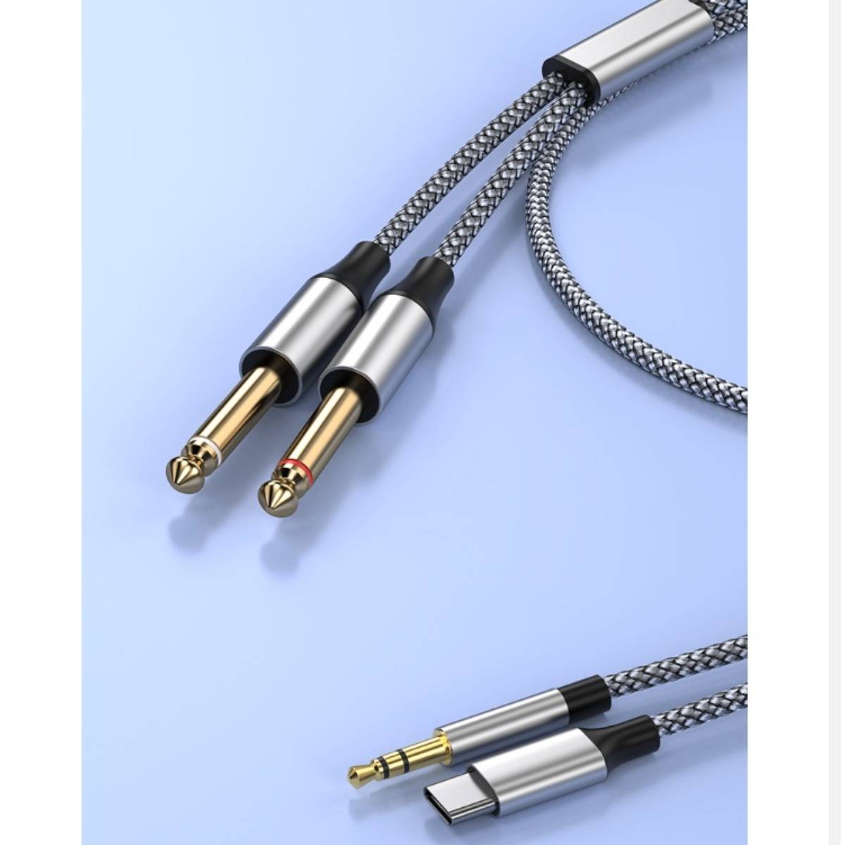Geflochtenes Audiokabel mit 1/4-Zoll- und USB-C-Anschlüssen auf hellblauem Hintergrund.