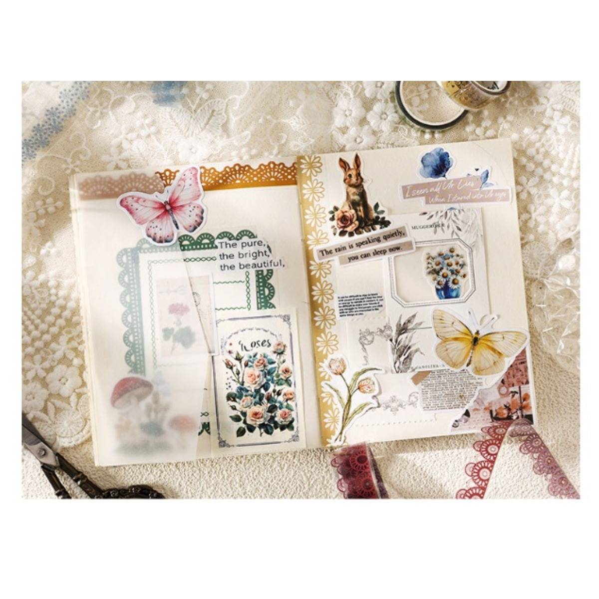 Offenes Scrapbook-Doppelseite mit Schmetterlingen, Blumenstickern und Collage-Elementen auf einem mit Spitze bedeckten Tisch, mit Zitaten und dekorativen Papier-Ephemera.