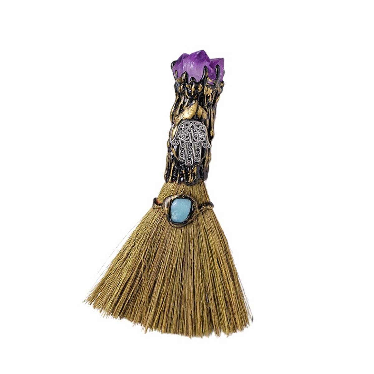 Dekorativer Miniatur-Besenstecker mit violettem Kristallaufsatz, silbernem Elefantencharm und blauem Edelstein auf einem hellbeigefarbigen Borsten-Rock.