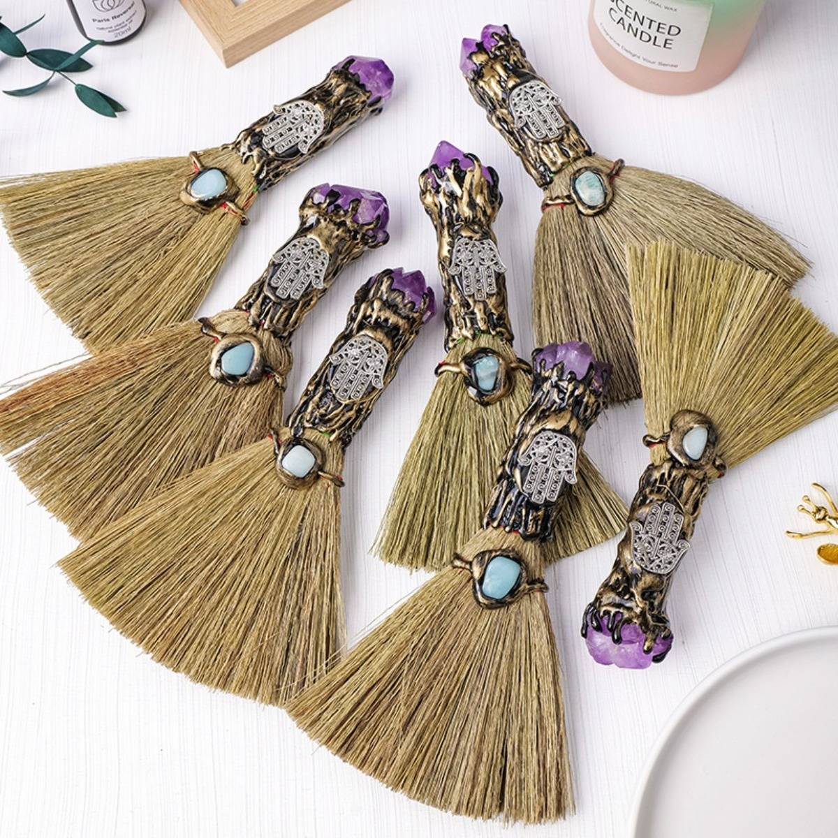 Fünf dekorative Quasten-Wandbehänge mit violett-goldenen Akzenten und Türkissteinen, auf einer weißen Oberfläche angeordnet.