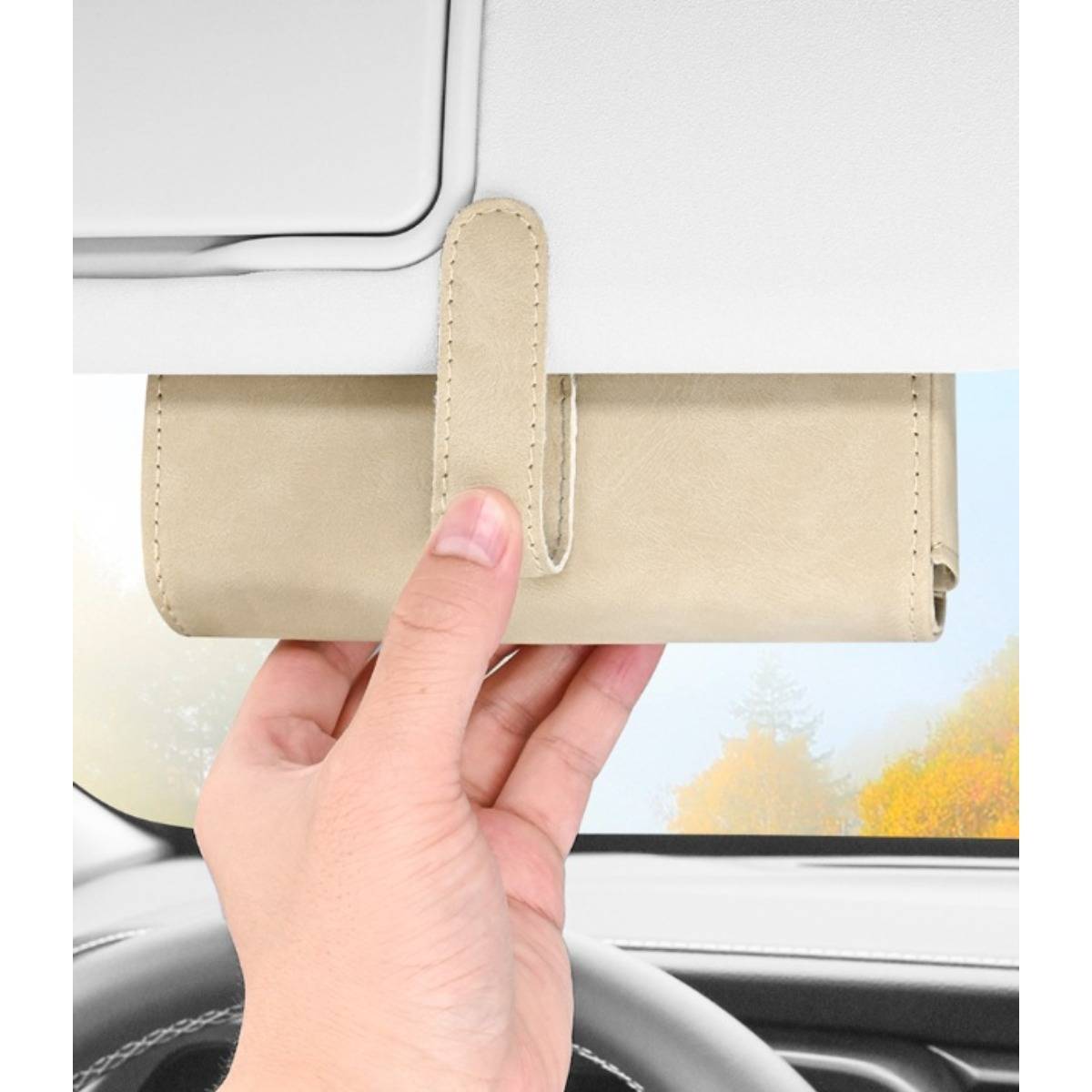 Hand, die einen beige Visierorganizer hält, der an einer Autosonnenschutzblende neben der Windschutzscheibe befestigt ist.