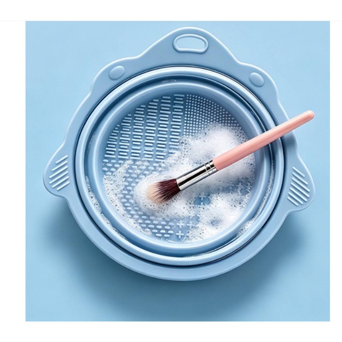 Makeup-Pinsel wird in einer blauen Schüssel mit Seifenwasser gewaschen.
