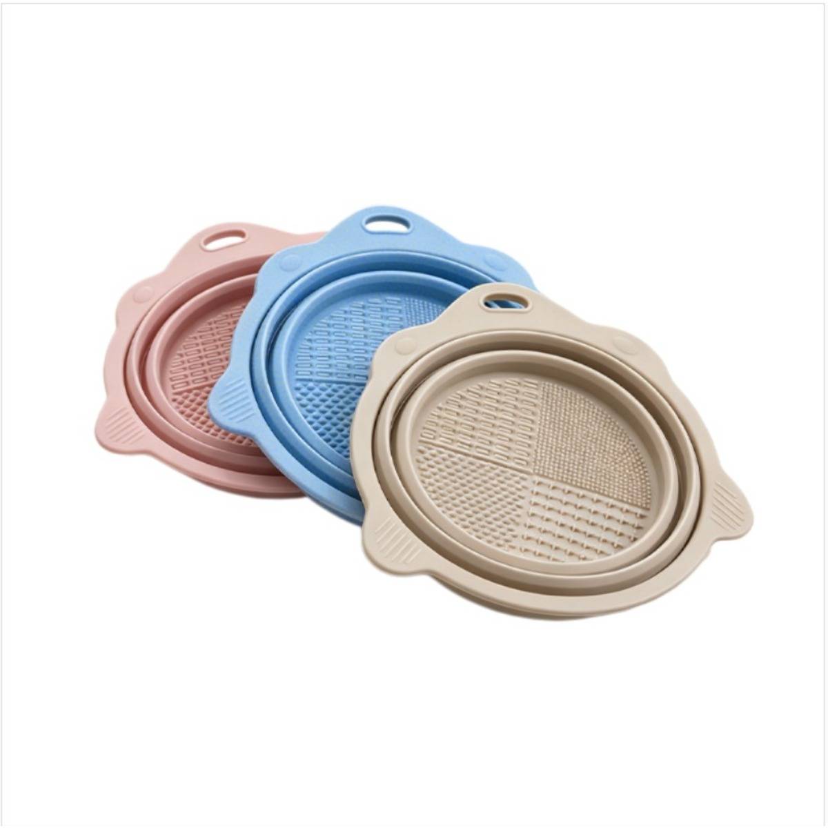 Drei runde Silikonlebensmittelsiebe oder Deckel in Rosa, Blau und Beige, die auf weißem Hintergrund übereinander gestapelt sind.