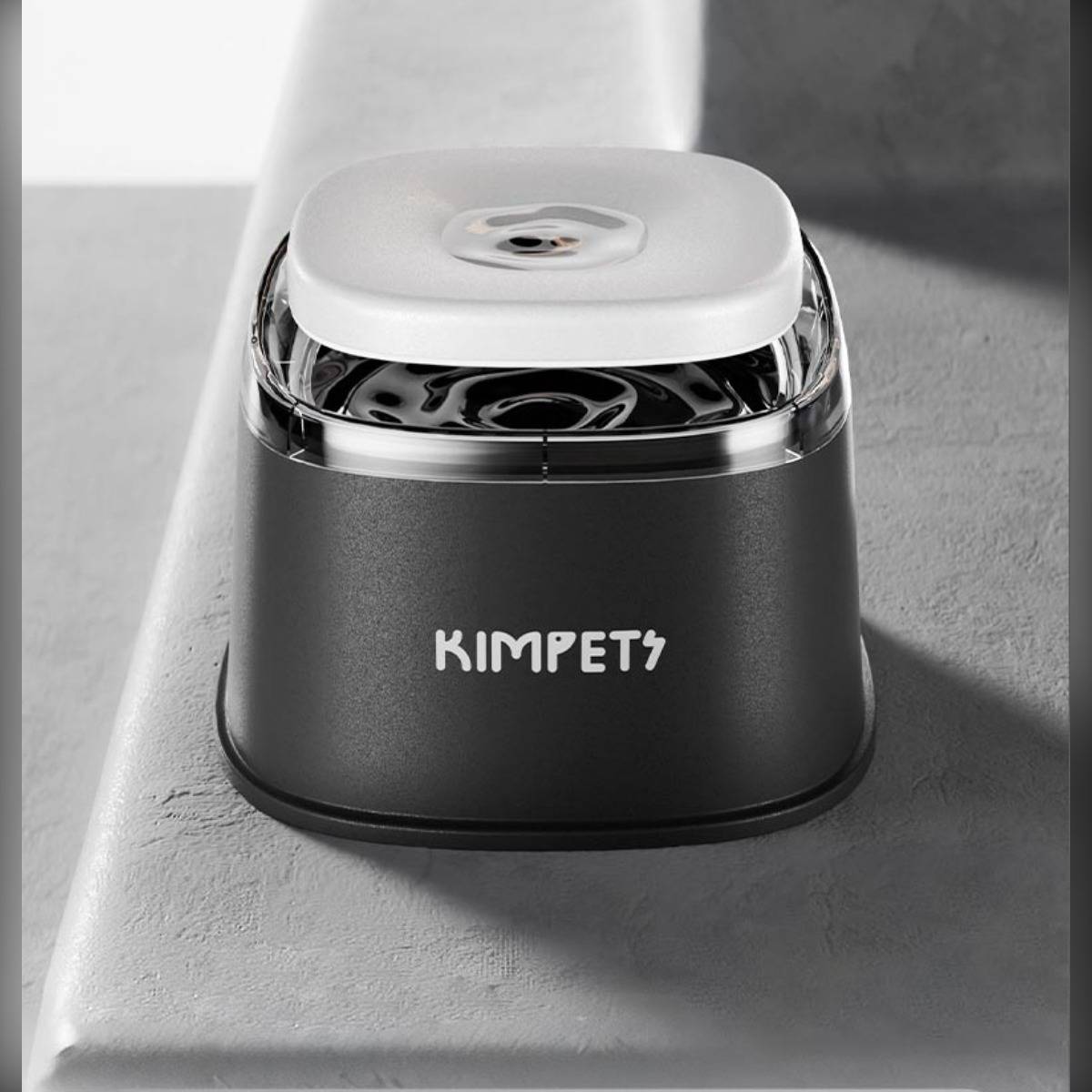 Kompakte schwarze KIMPETS-Haustierbrunnen mit weißer Oberseite, gezeigt auf einer grauen Oberfläche.
