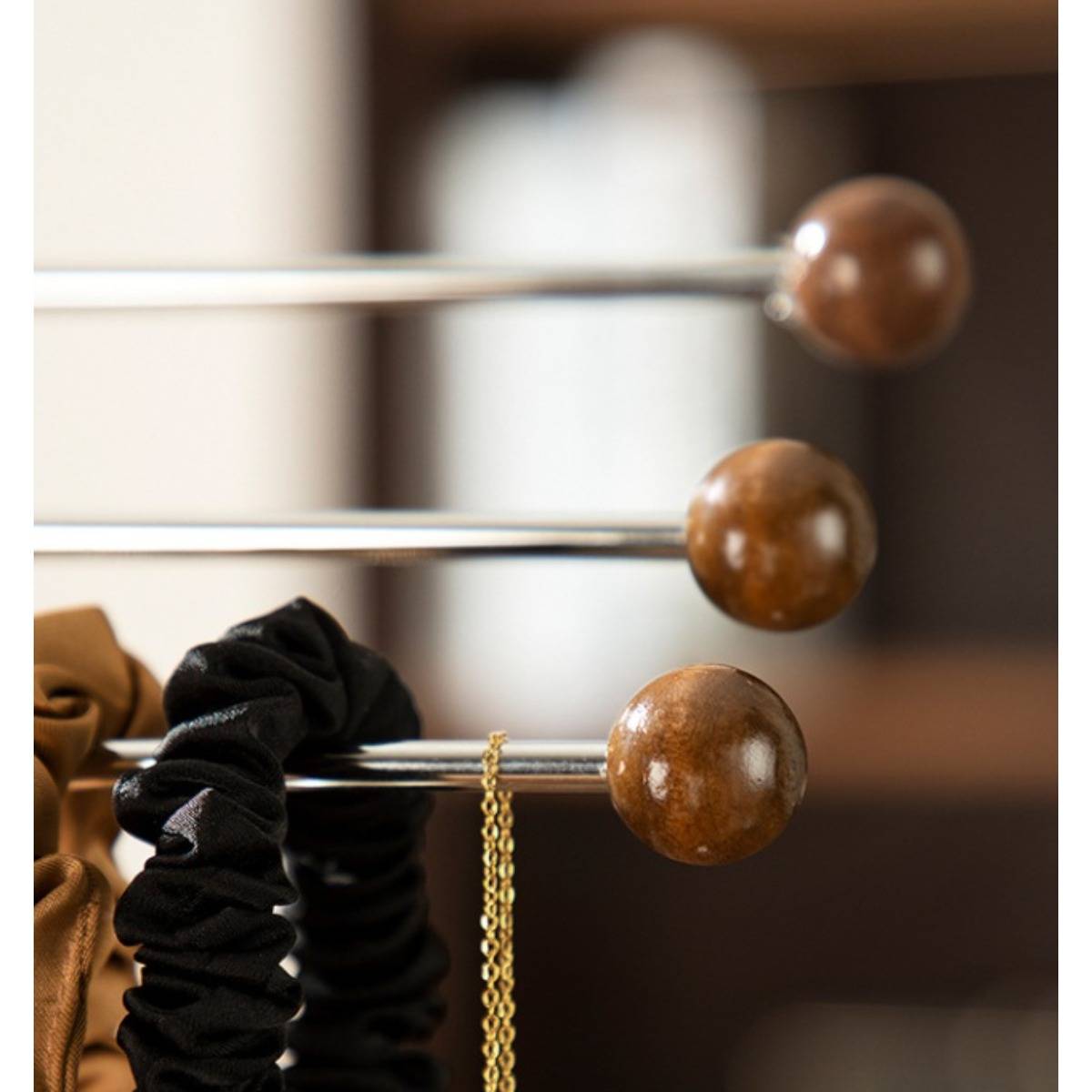 Nahaufnahme mehrerer Metallstäbe mit hölzernen Kugelenden, die braune und schwarze Stoff-Haargummis halten, mit einer goldenen Kette, die von einem Stab herabhängt.