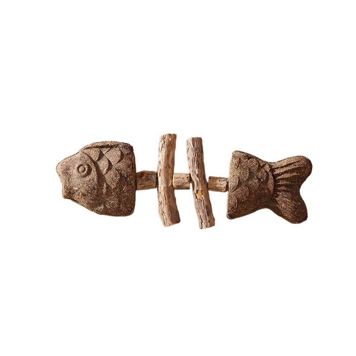 Eine rustikale Fischgerippe-Dekoration aus geschnitztem Holz oder Stein, mit zwei Fischköpfen/-schwänzen, die durch zweigähnliche Knochen auf weißem Hintergrund verbunden sind.