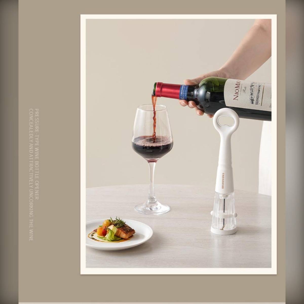 Eine Hand gießt Rotwein in ein Glas neben einer angerichteten Vorspeise und einem weißen Flaschenöffner auf einem Tisch.