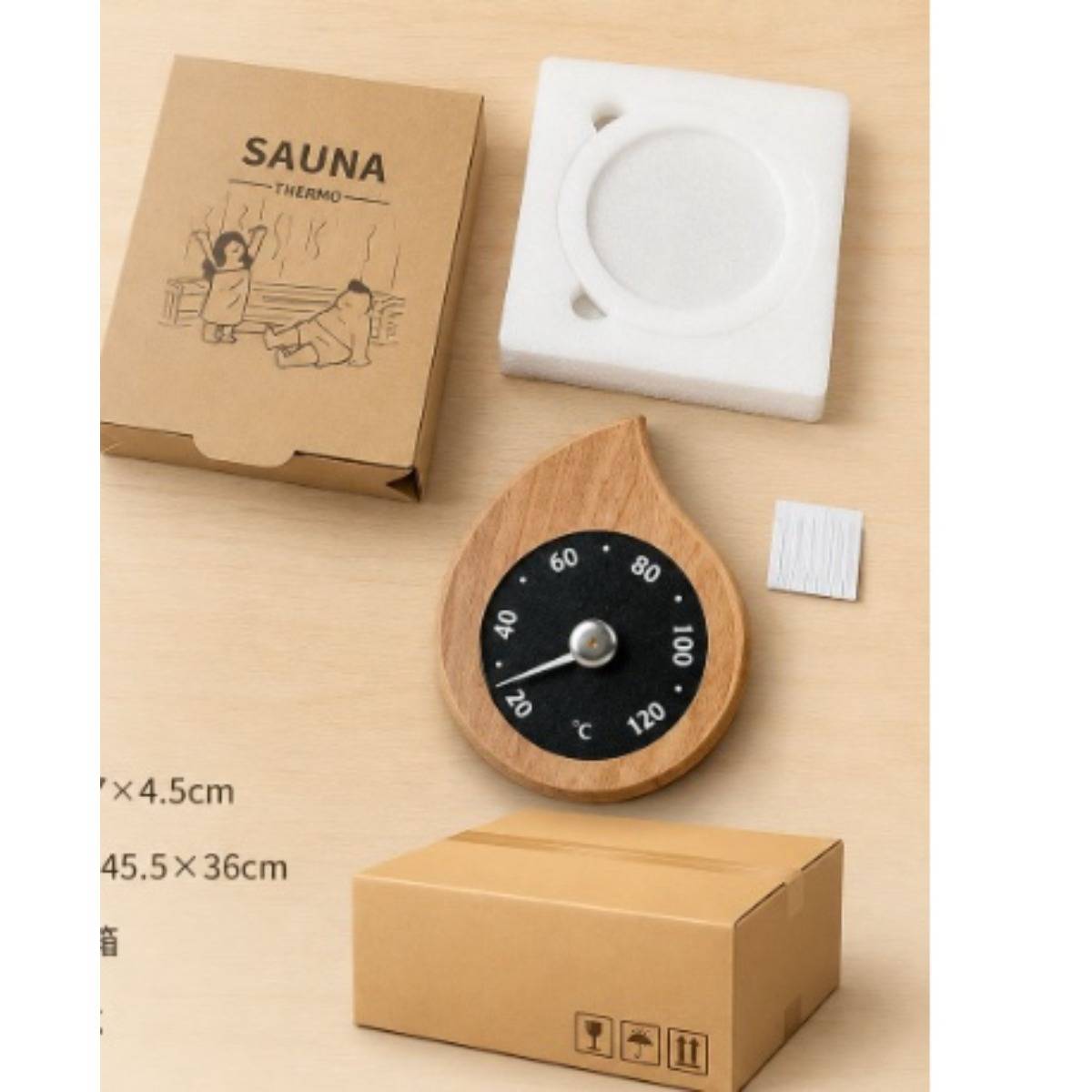 Produktfoto eines Saunen-Thermometer-Sets: Holz-Tropfenform-Thermometerzifferblatt, Karton, weiße Befestigungsvorrichtung und Verpackung mit „SAUNA THERMO"-Text.
