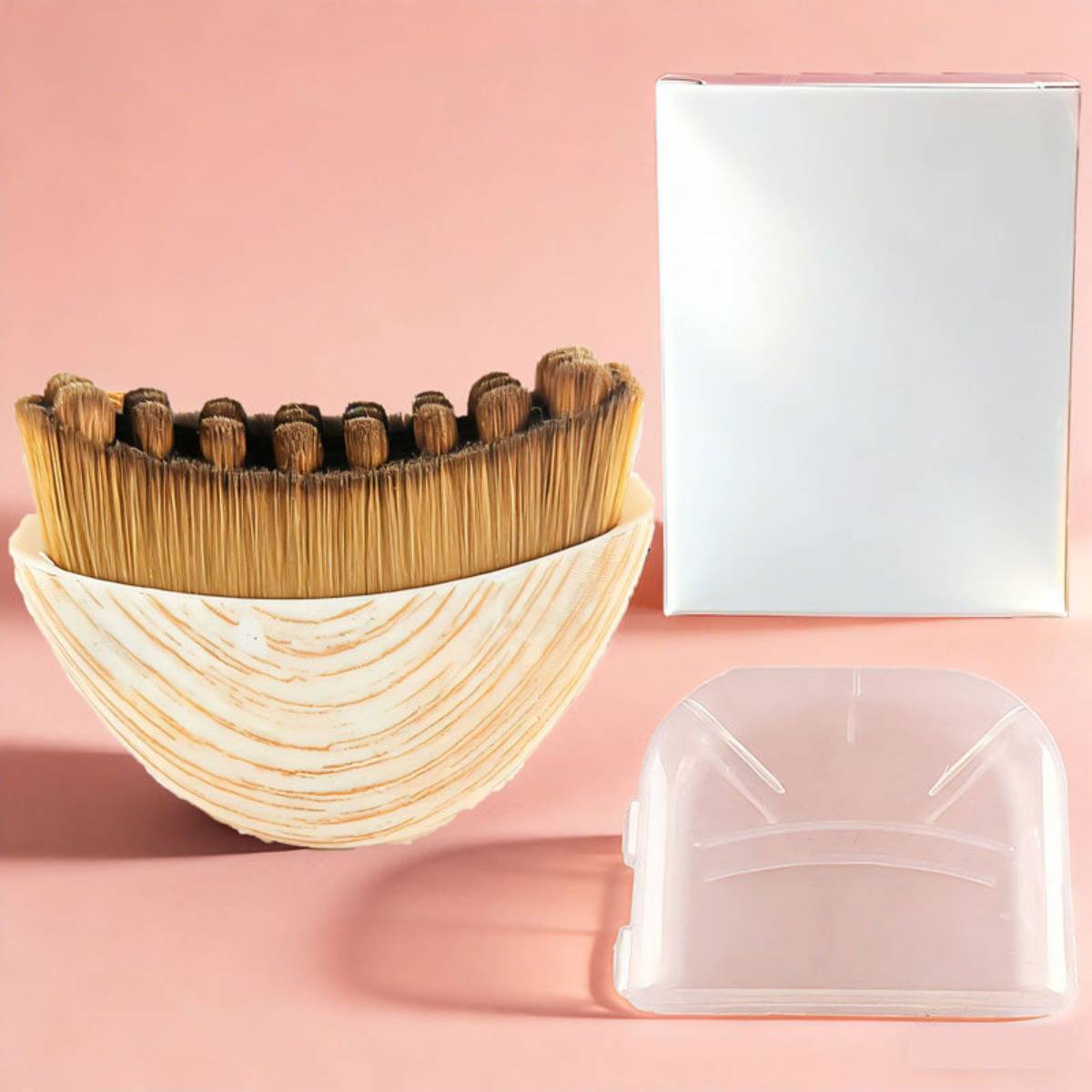 Holzbürste mit weißem geschnitztem Muschelschalenbehälter, einer leeren weißen Schachtel und einer durchsichtigen Kunststoffabdeckung auf rosa Hintergrund.