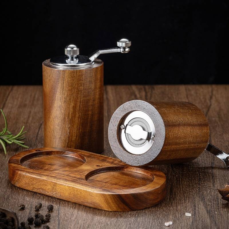 Holzmanuelle Pfeffer- und Salzschleifer mit einem ovalen Holztablett auf einer rustikalen Tischplatte.
