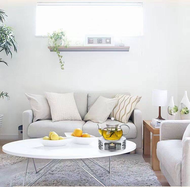 Helles modernes Wohnzimmer mit zwei hellen Sofas, rundem weißem Couchtisch, Fensterbrett mit Pflanzen und weicher, neutraler Dekoration.