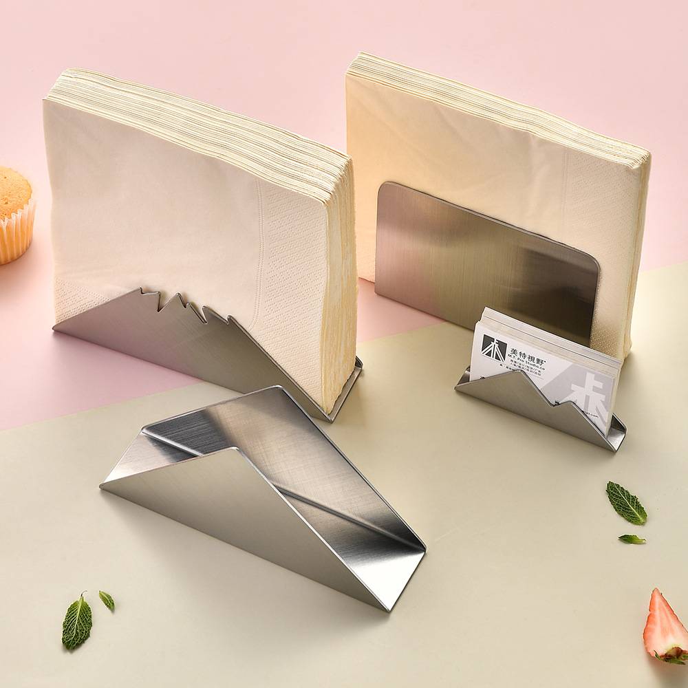 Zwei Metallbuchstützen halten Bücher aufrecht, eine mit einem Kartenhälter-Schlitz und eine mit flacher Stütze auf einer pastellfarbenen Tischplatte.