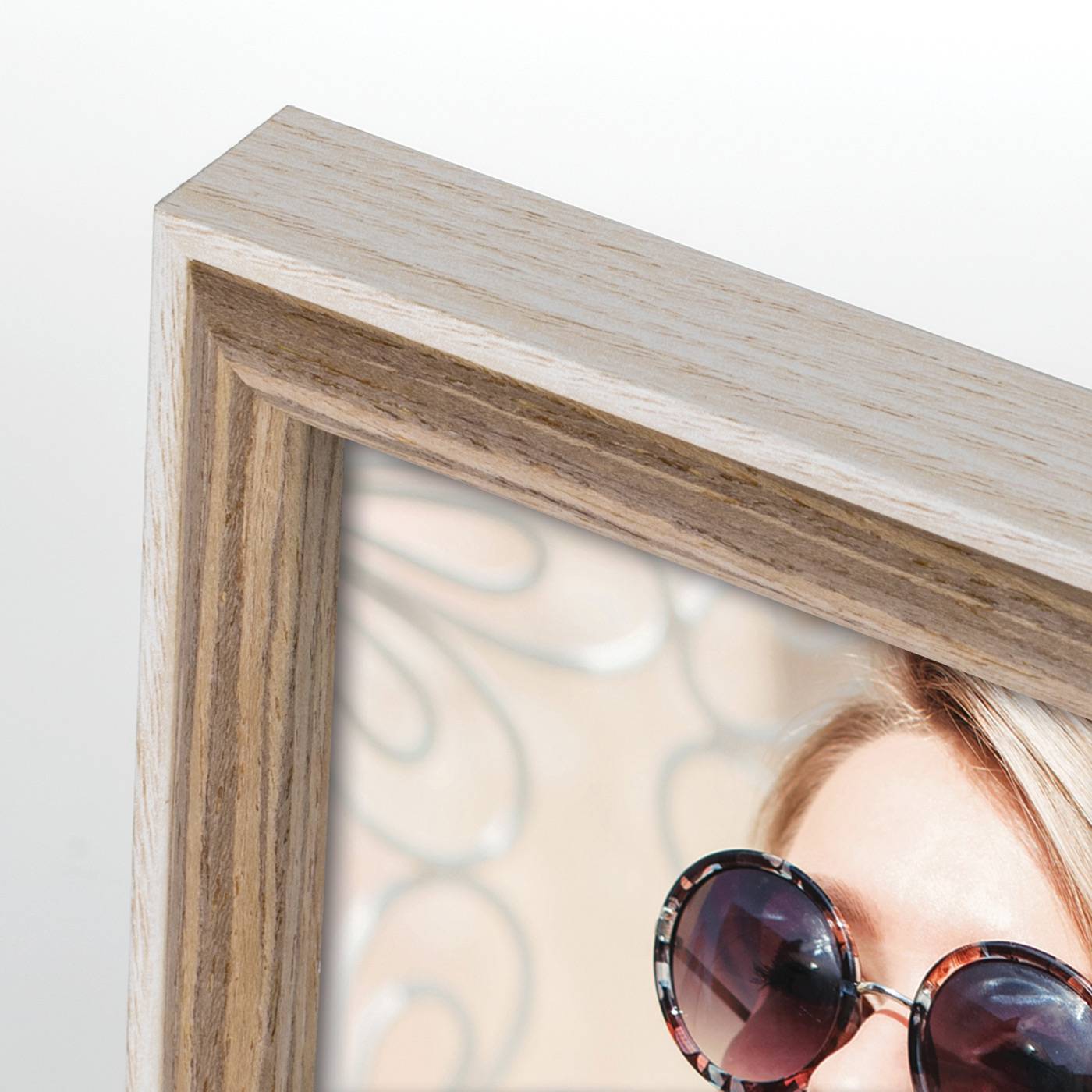 Nahaufnahme eines Holzbilderrahmens, der einen Teil des Gesichts einer Frau zeigt, die eine runde Sonnenbrille trägt.