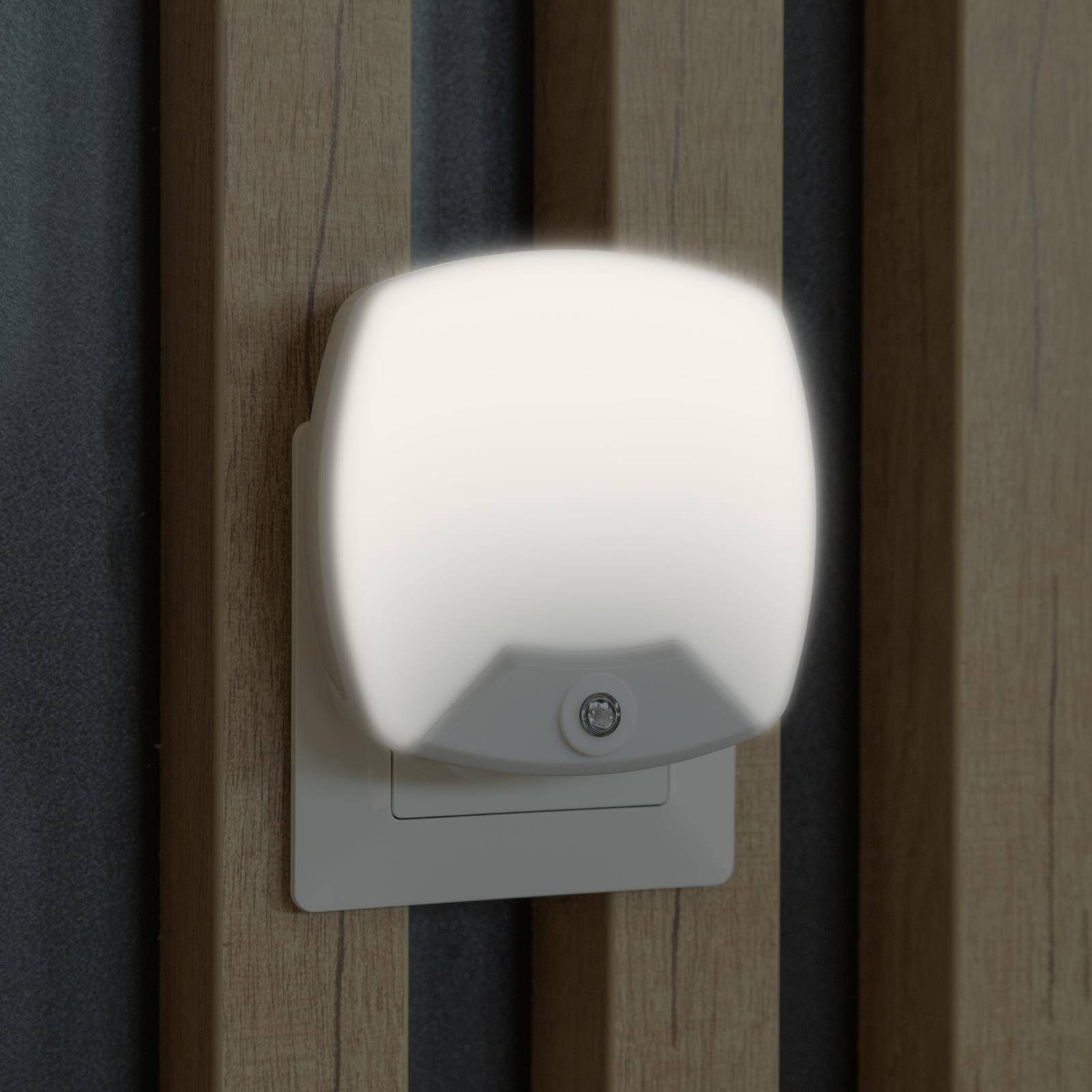 Weiße an der Wand montierte Nachtleuchte, die auf einer Holzlattenwand leuchtet.