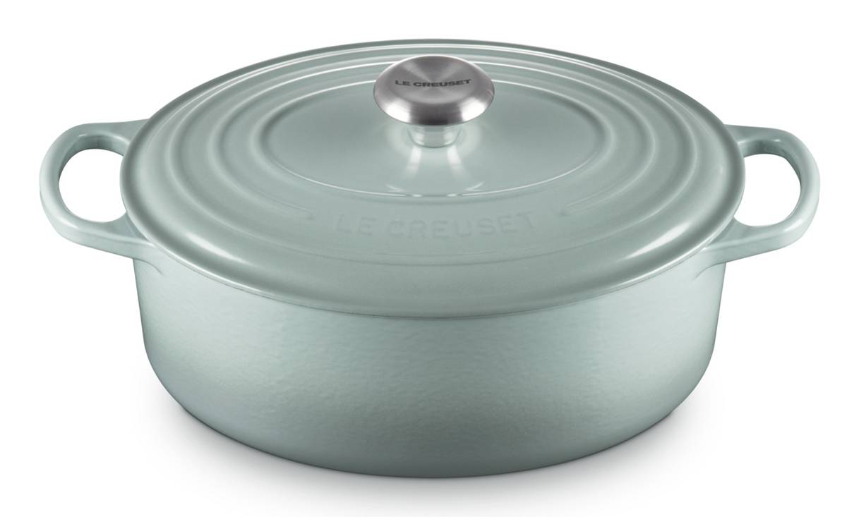 Hellblaue runde emaillierte Cocotte mit Deckel und Griffen an den Seiten auf weißem Hintergrund.