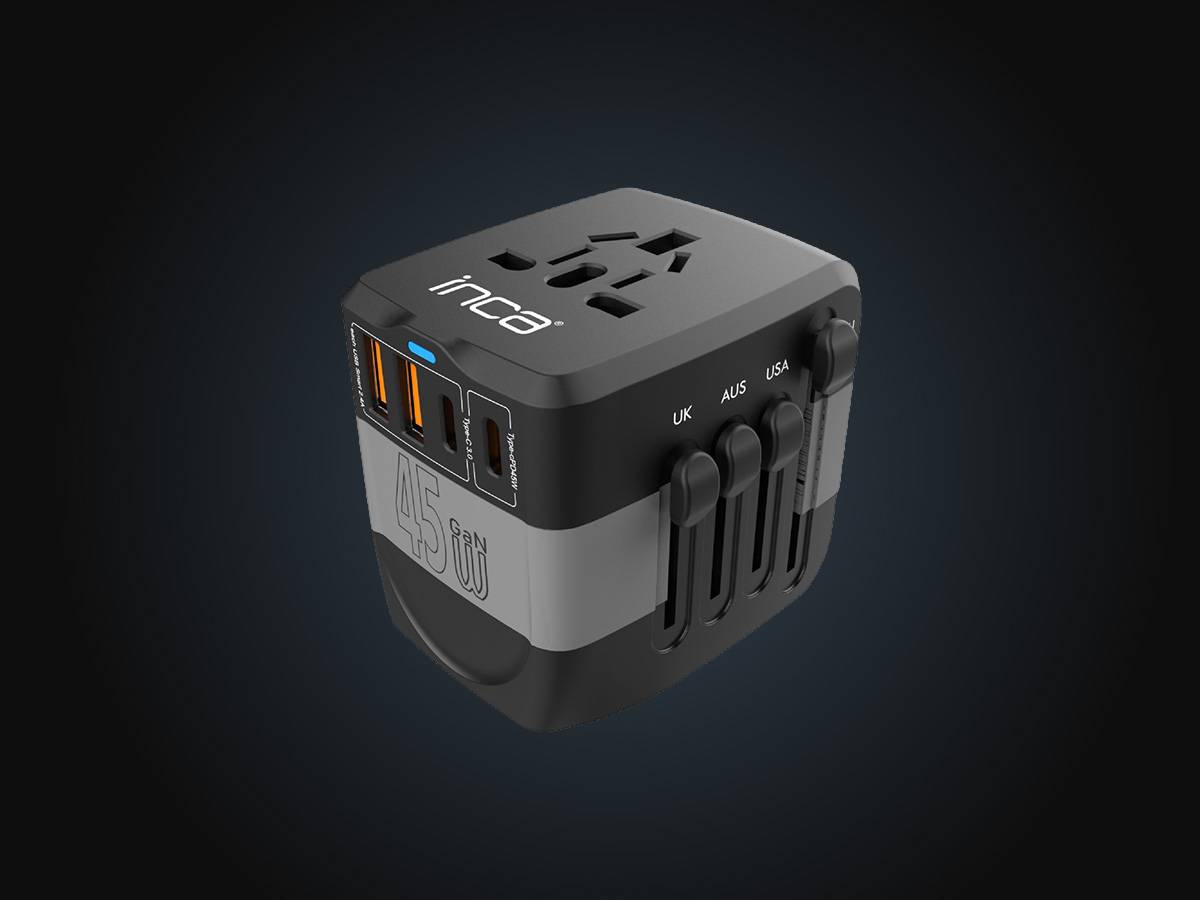 Universeller Reiseadapter-Würfel mit mehreren USB-Anschlüssen und ausklappbaren Steckertypen mit Beschriftung UK, AUS und USA.