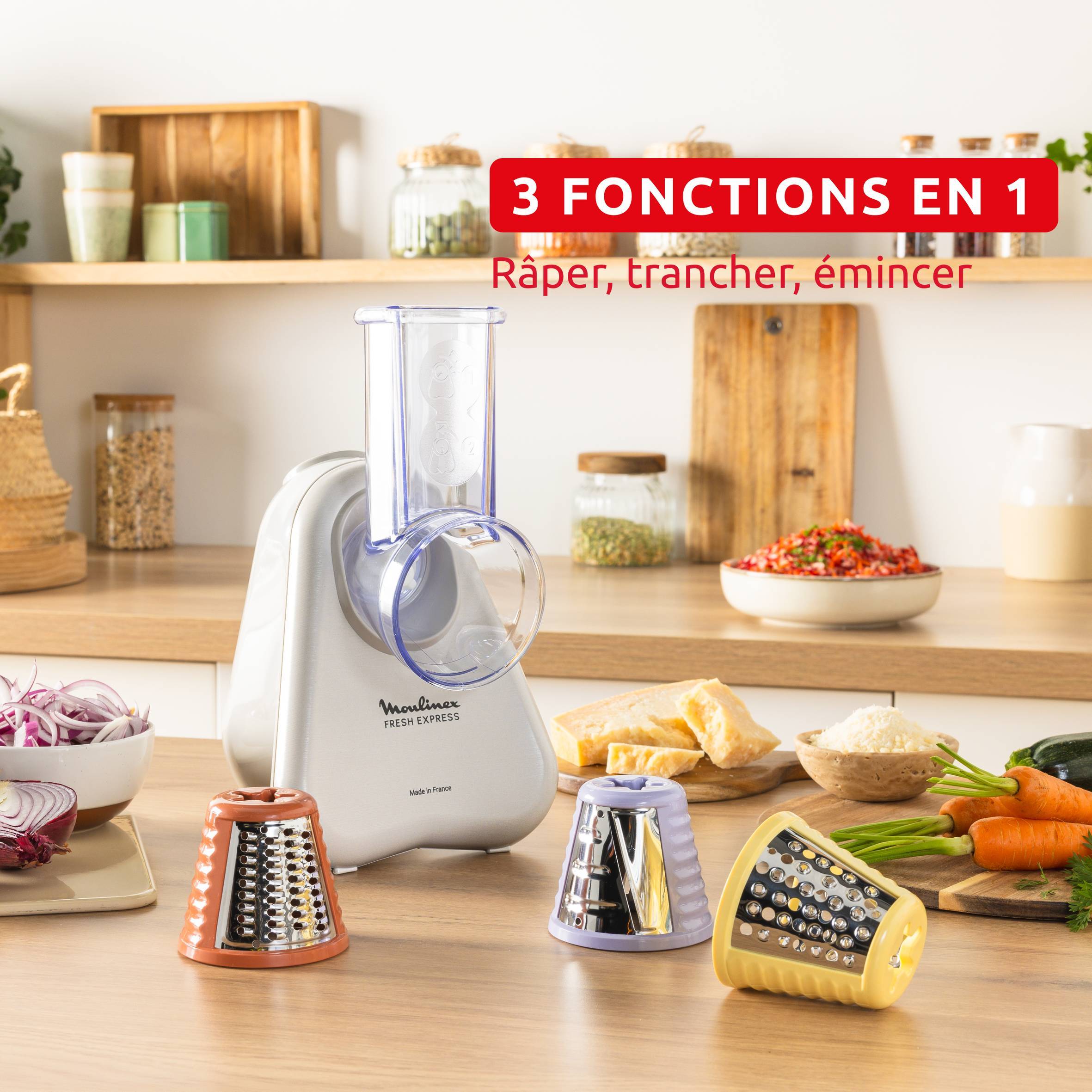 Lebensmittelschneider mit drei austauschbaren Trommeln zum Reiben, Schneiden und Hobeln, abgebildet mit Gemüse und Käse; Text lautet „3 FUNKTIONEN IN 1