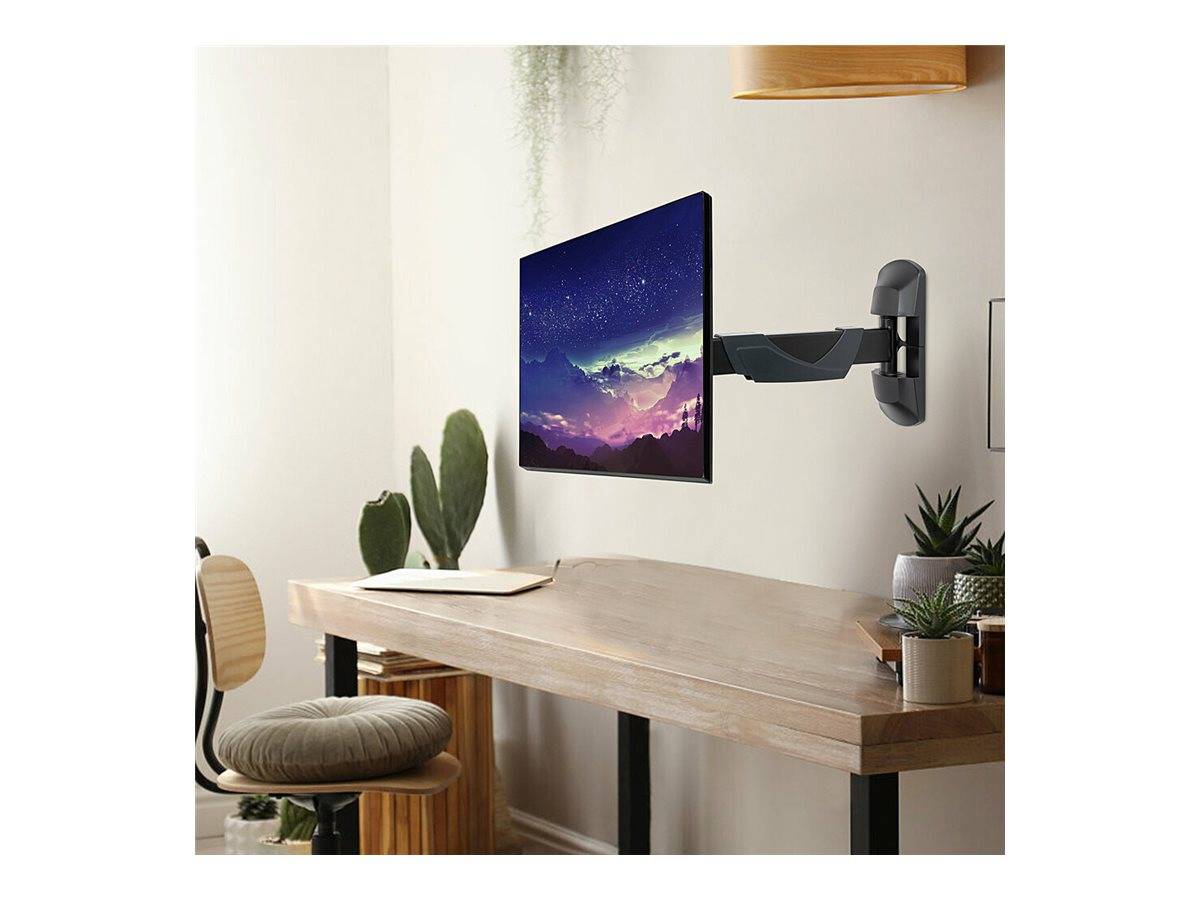 Flacher Fernseher auf einer Wandhalterung über einem Schreibtisch in einem modernen Homeoffice montiert, mit einem Stuhl, Pflanzen und einem Laptop in der Nähe.