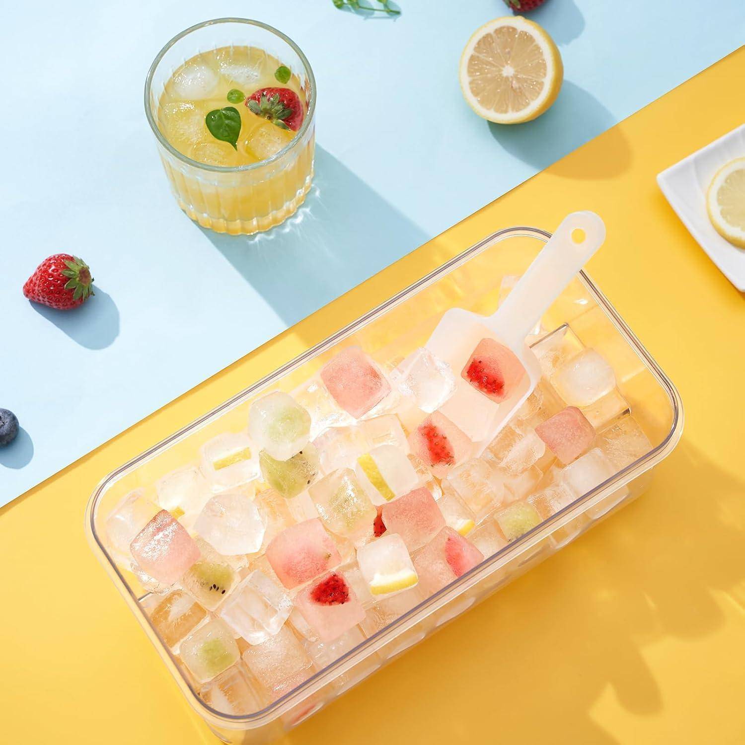 Draufsicht auf ein Eiswürfelbehälter für Fruchtsaft mit assortiertem Obst-Eiswürfeln, ein Glas Limonade und geschnittene Zitrusfrüchte auf blauem und gelbem Hintergrund.