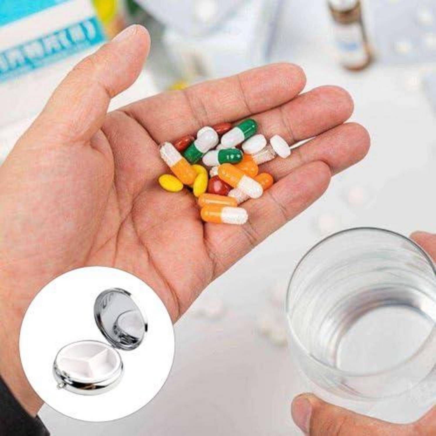 Hand, die verschiedene Kapseln und Tabletten neben einem Glas Wasser hält, mit einer Vergrößerung, die einen Pillendosierer zeigt.