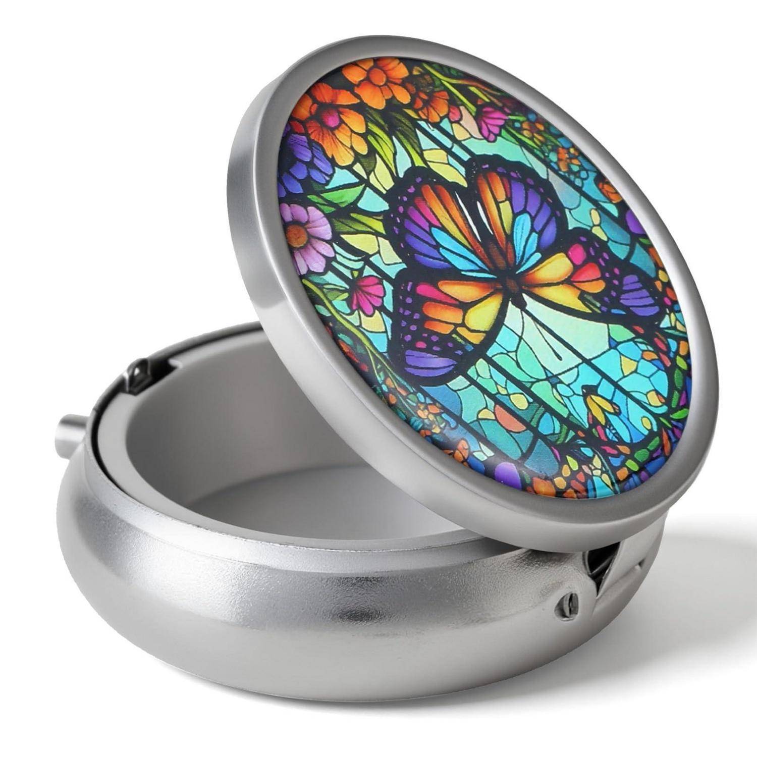 Silberner runder Kompaktspiegel mit geöffnetem Deckel, der einen bunten Schmetterling und ein Design im Buntglas-Stil auf der Oberseite zeigt.