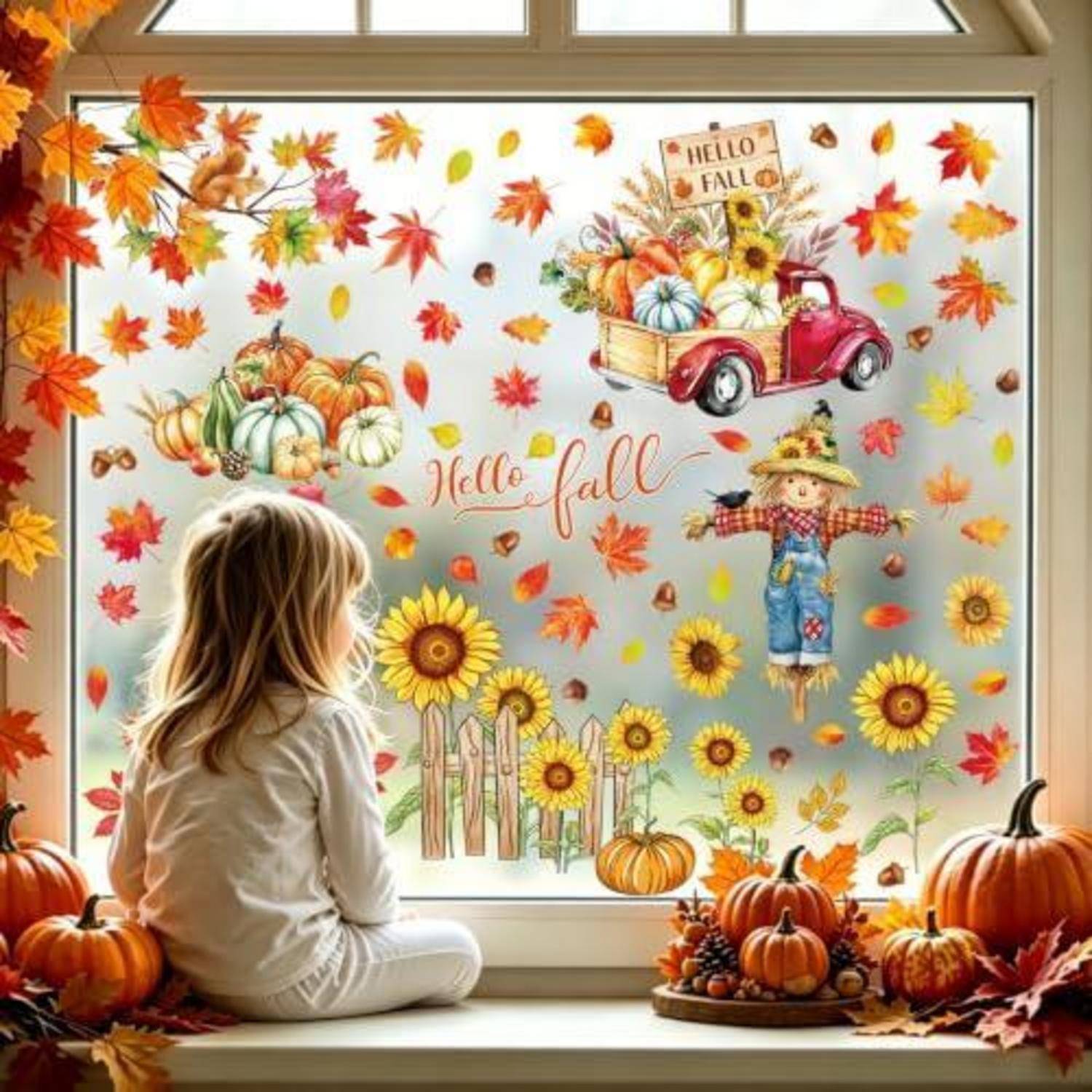 Ein kleines Kind sitzt auf einer Fensterbank und schaut sich eine herbstliche Schaufensterdekoration an, auf der „Hallo Herbst", Kürbisse, Sonnenblumen, Blätter und ein roter Lastwagen zu sehen sind.