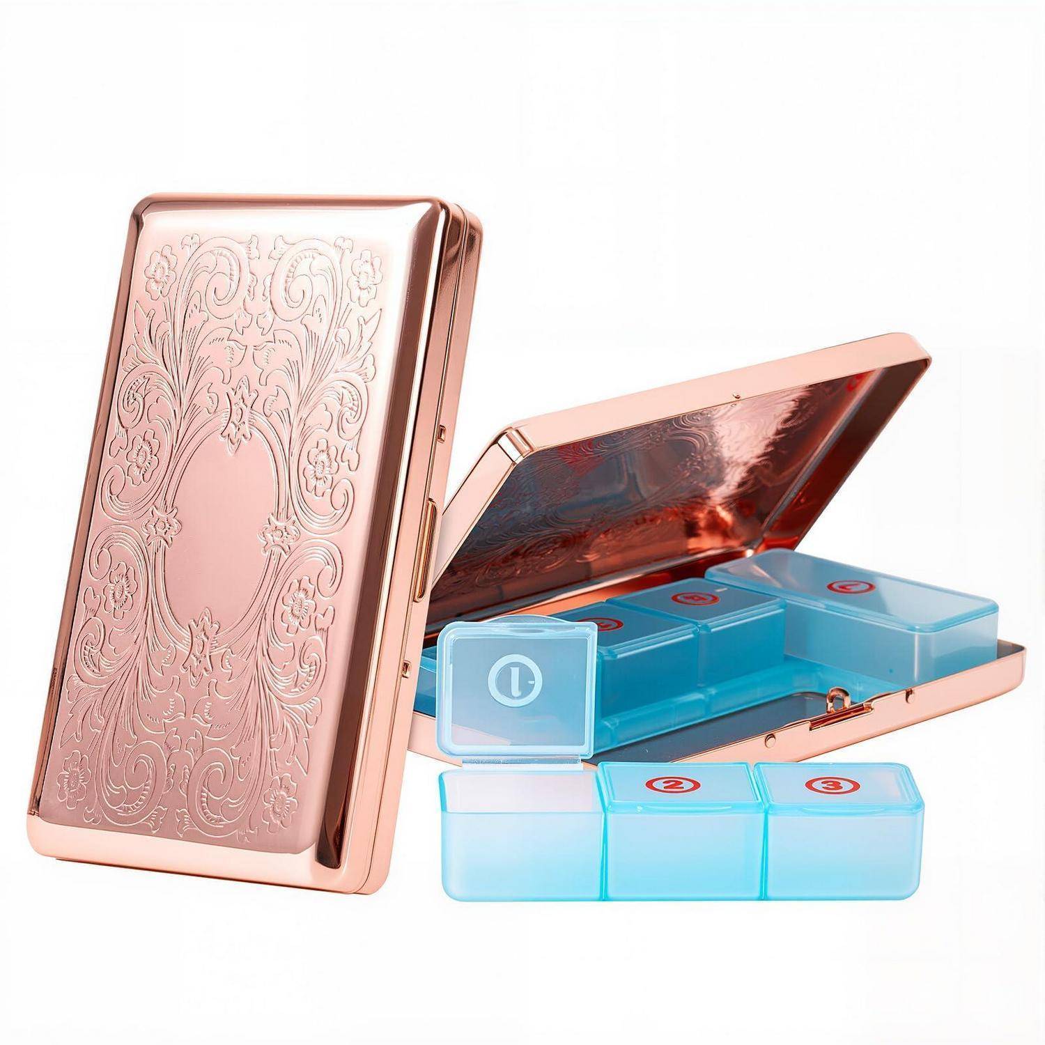Roségoldenes Metallpillengehäuse mit graviertem Blumenmuster, aufgeklappt mit blauen durchscheinenden Pillenfächern und abnehmbarem Tablett.