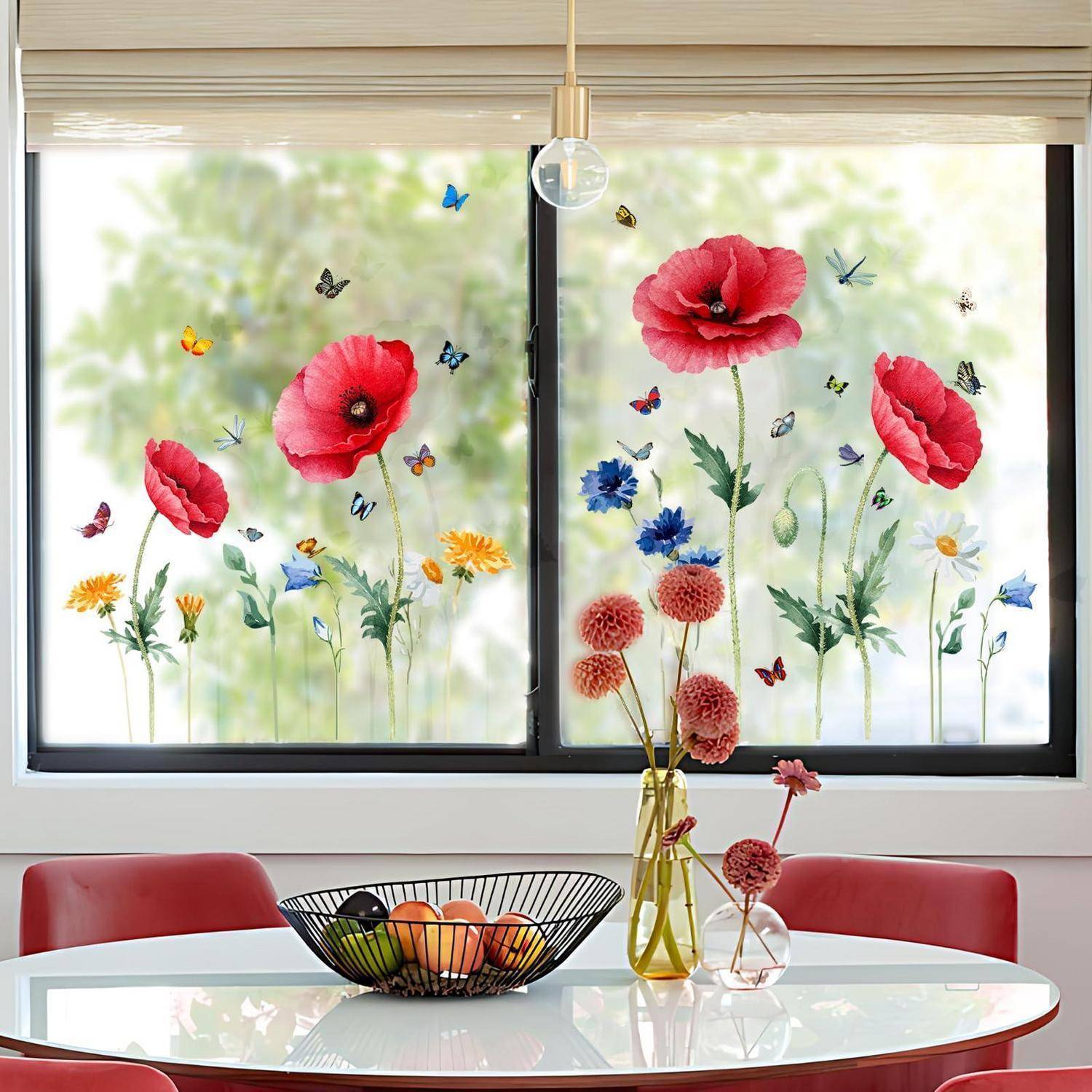 Dekorative Blumenfensteraufkleber auf einem großen Fenster mit schwarzem Rahmen, mit roten Mohnblumen, Schmetterlingen und Blumen, die über einem Esstisch mit roten Stühlen sichtbar sind.