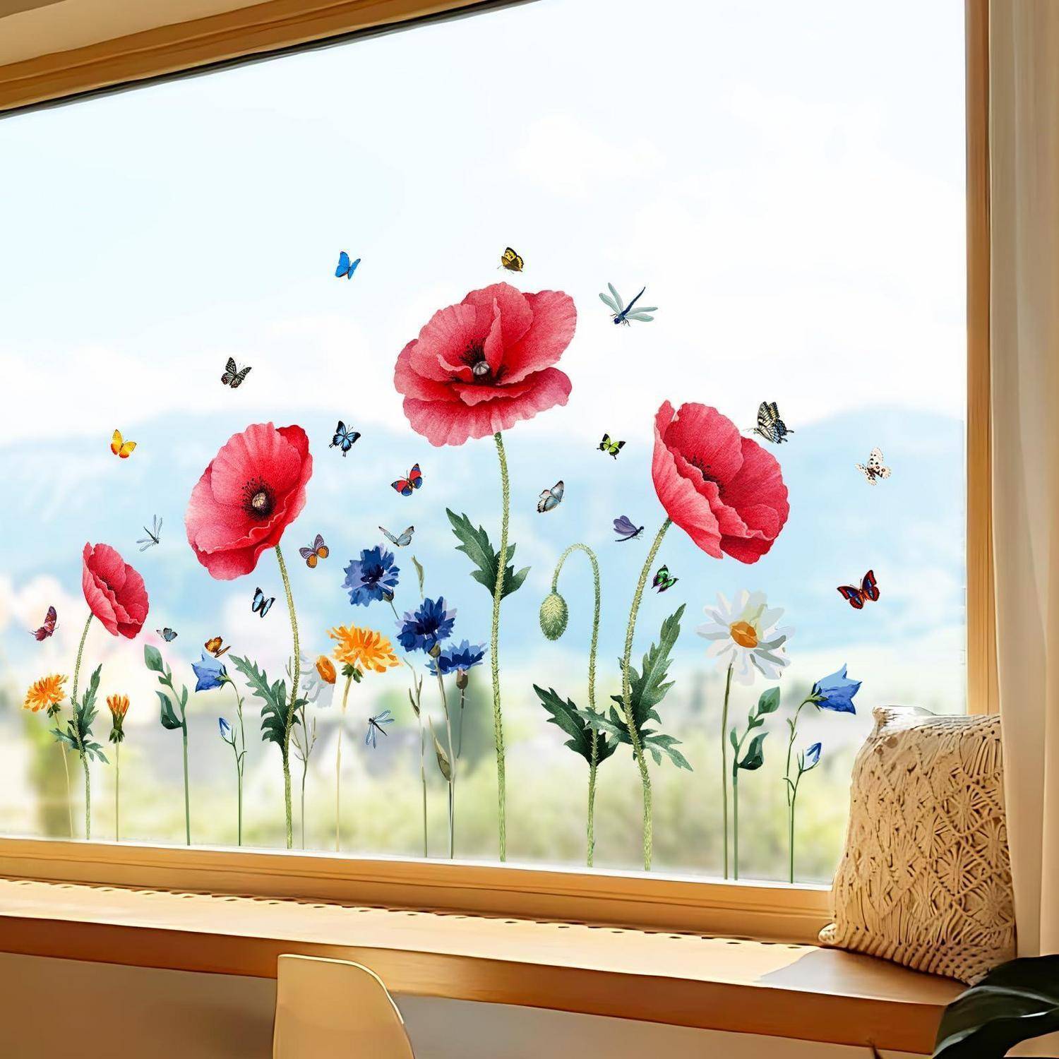 Dekoratives Blumenfenster-Aufkleber mit roten Mohnblumen, Wildblumen und Schmetterlingen auf einem hellen Fenster über einem Holzfenster Brett mit einem Kissen.