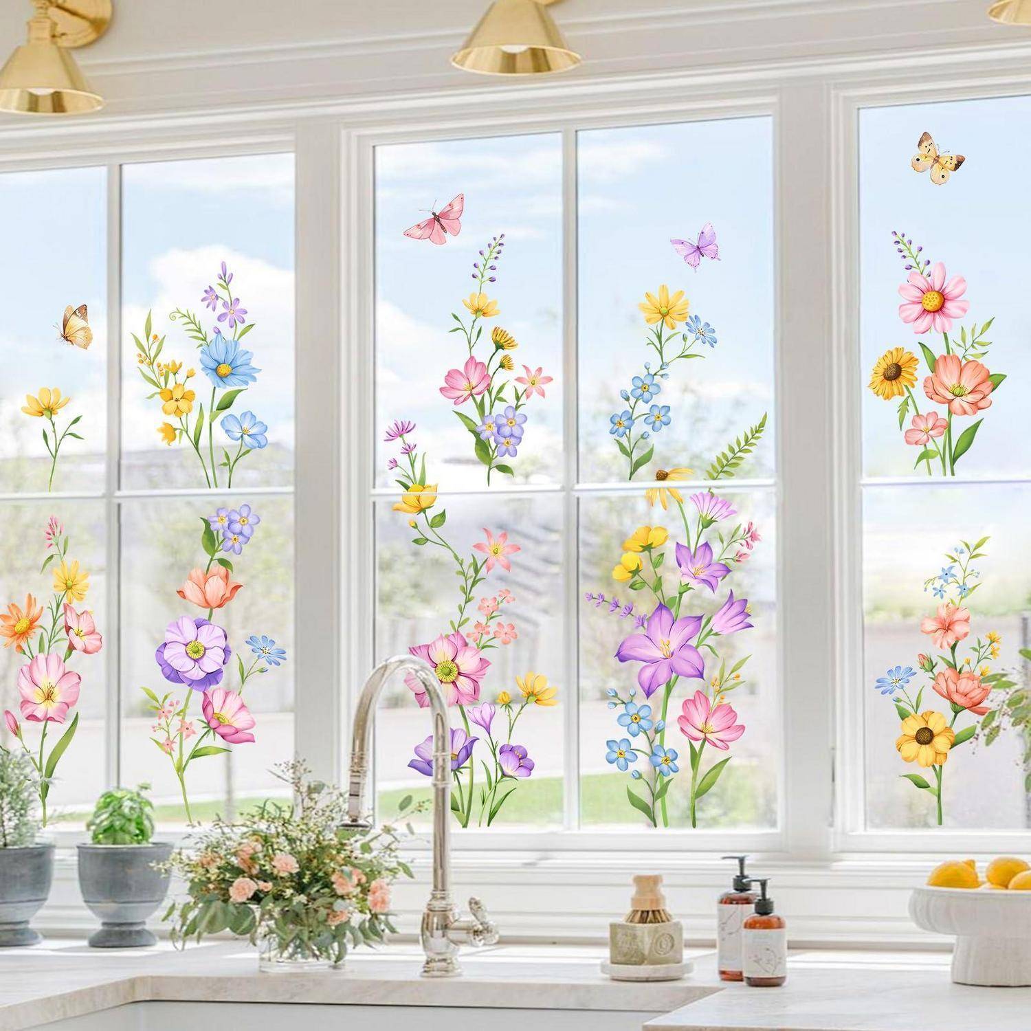 Helles Küchenfenster, das über einem Spülbecken und einer Arbeitsplatte mit bunten Blumen- und Schmetterlings-Fensteraufklebern dekoriert ist.
