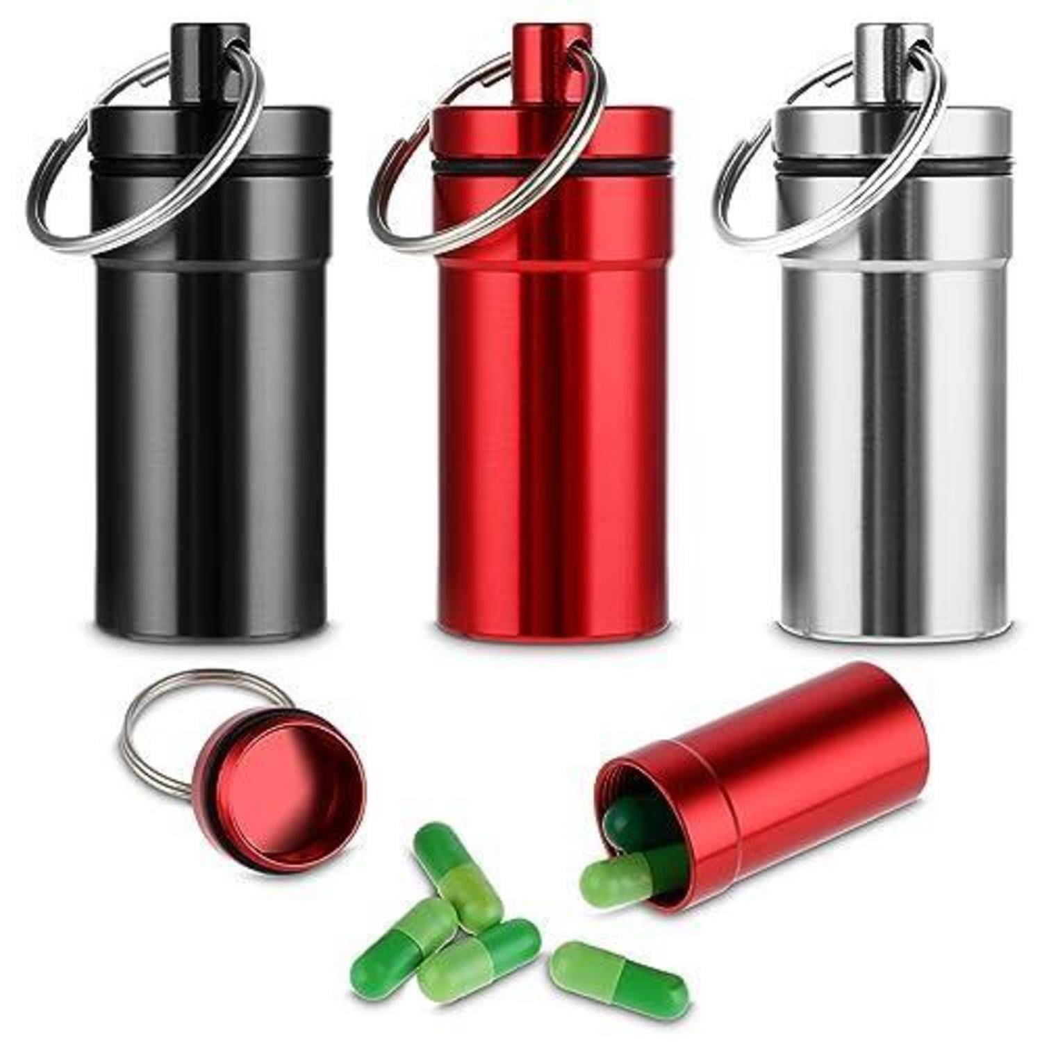 Drei Metall-Schlüsselanhänger-Pillenboxen in Schwarz, Rot und Silber, gezeigt mit Kapseln, die aus dem roten Behälter verschüttet sind.