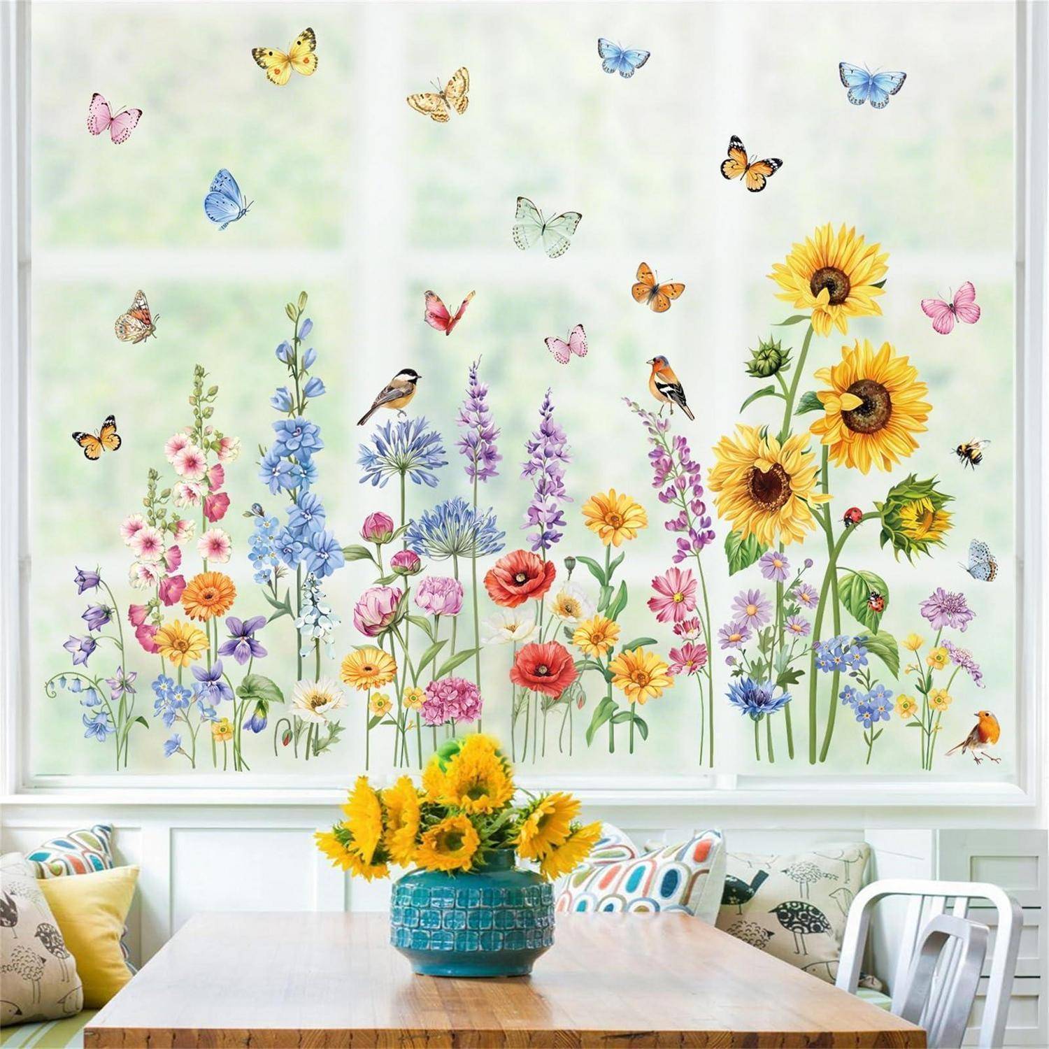 Helles Esszimmer mit floralem Fenstergemälde mit Schmetterlingen und Vögeln über einem Tisch mit Sonnenblumen in einer blauen Vase und gemusterten Kissen.