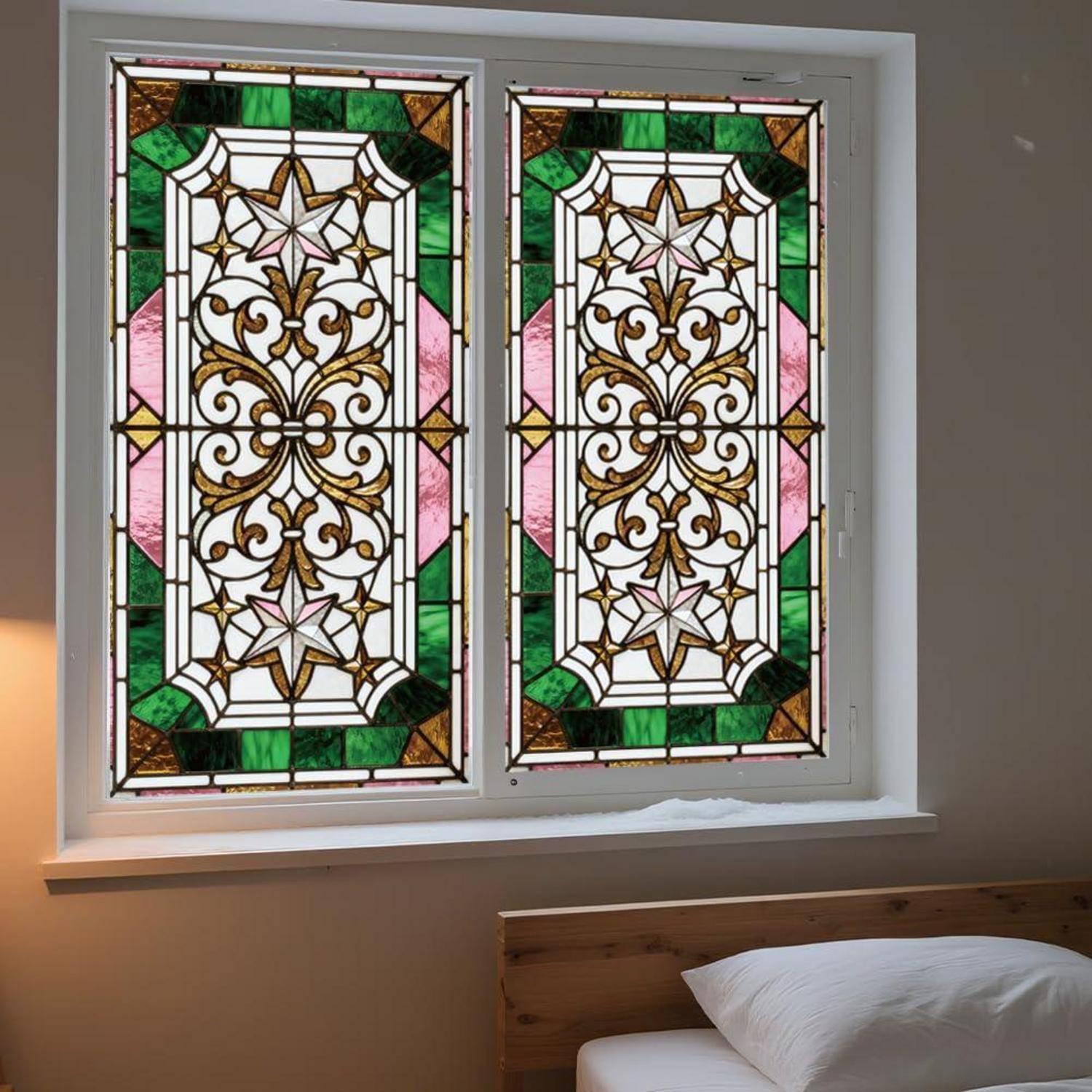 Bleiglasfenster mit symmetrischen Blüten- und Sternenmustern in Grün, Rosa und Bernsteinfarben, gefasst in einem weißen Rahmen über einem Bett.