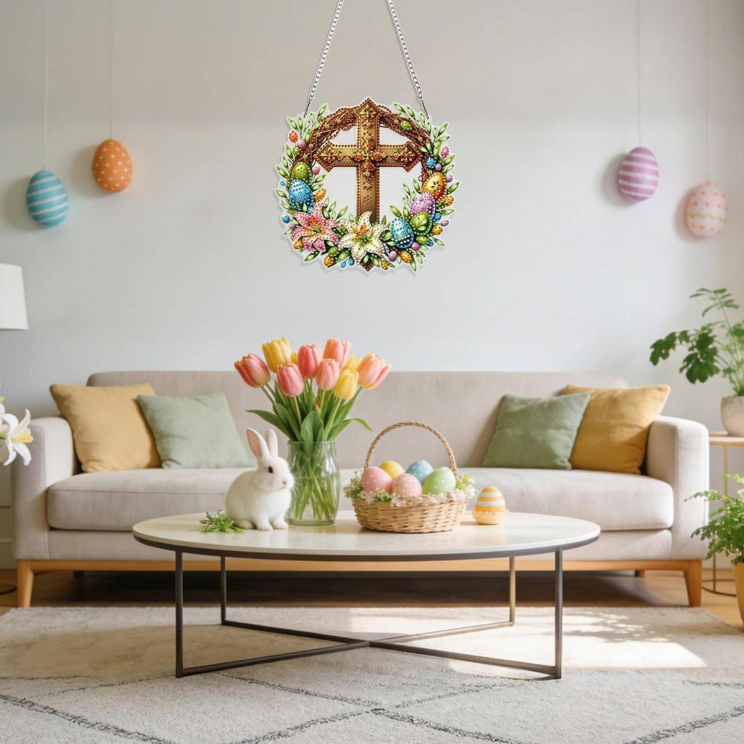 Osterdekoriertes Wohnzimmer mit beigem Sofa, Couchtisch, Tulpen, Hasen-Figur, pastellfarbenen Eiern und einem hängenden Blumenkreuz als Mittelpunkt.